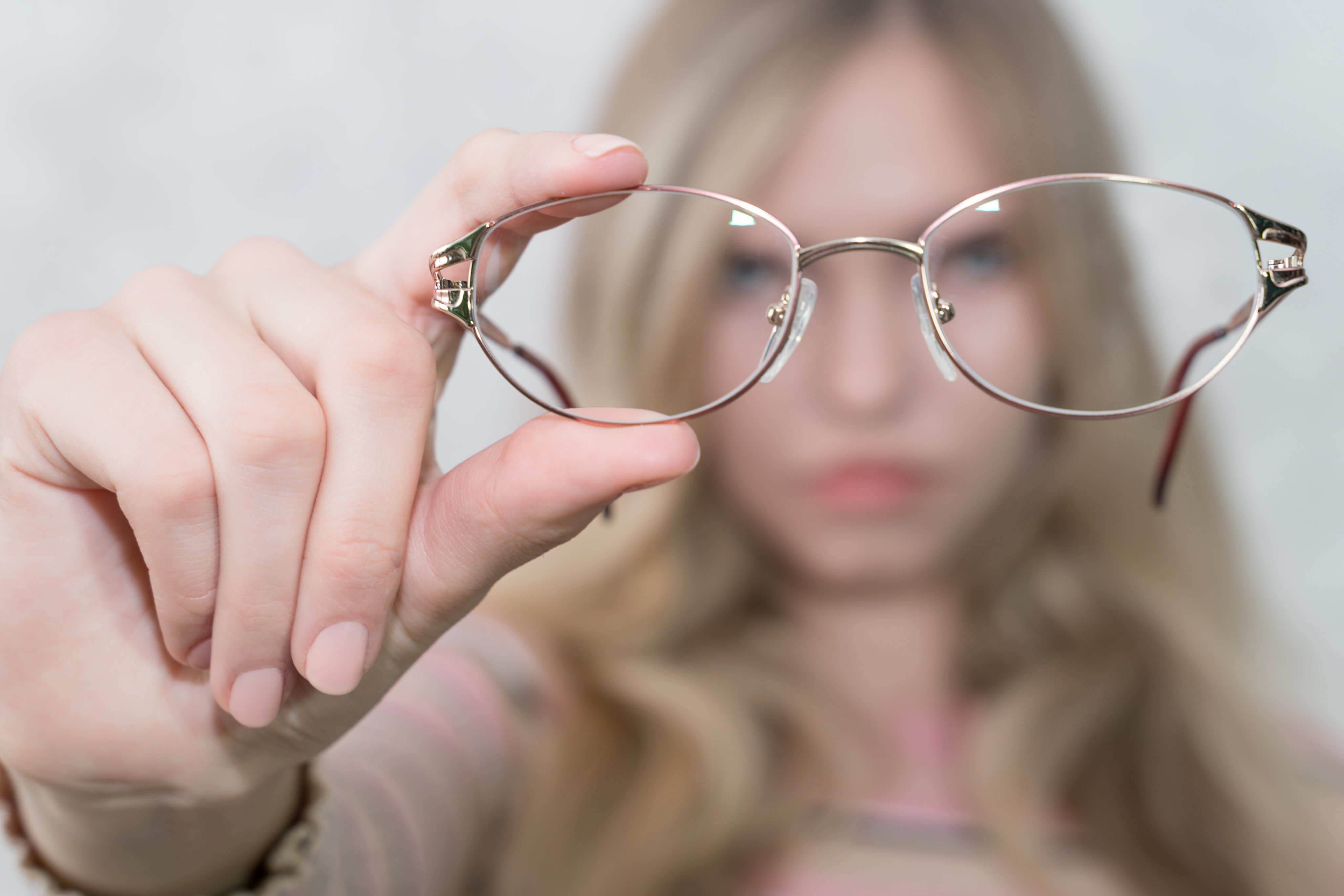 Child holding glasses in the foreground, representing childhood myopia and vision correction