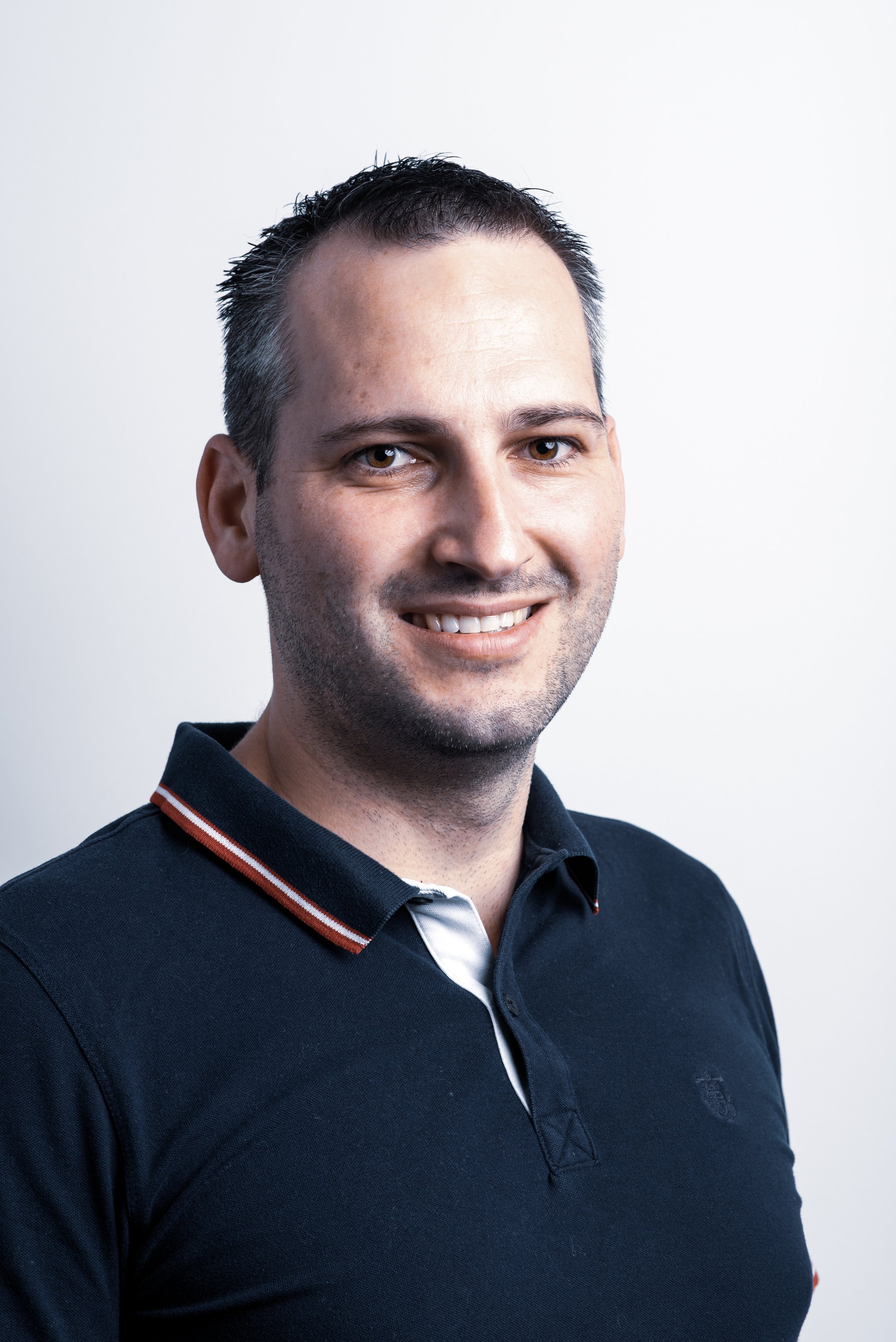 Professional portrait of a smiling Oertli employee wearing a dark polo shirt