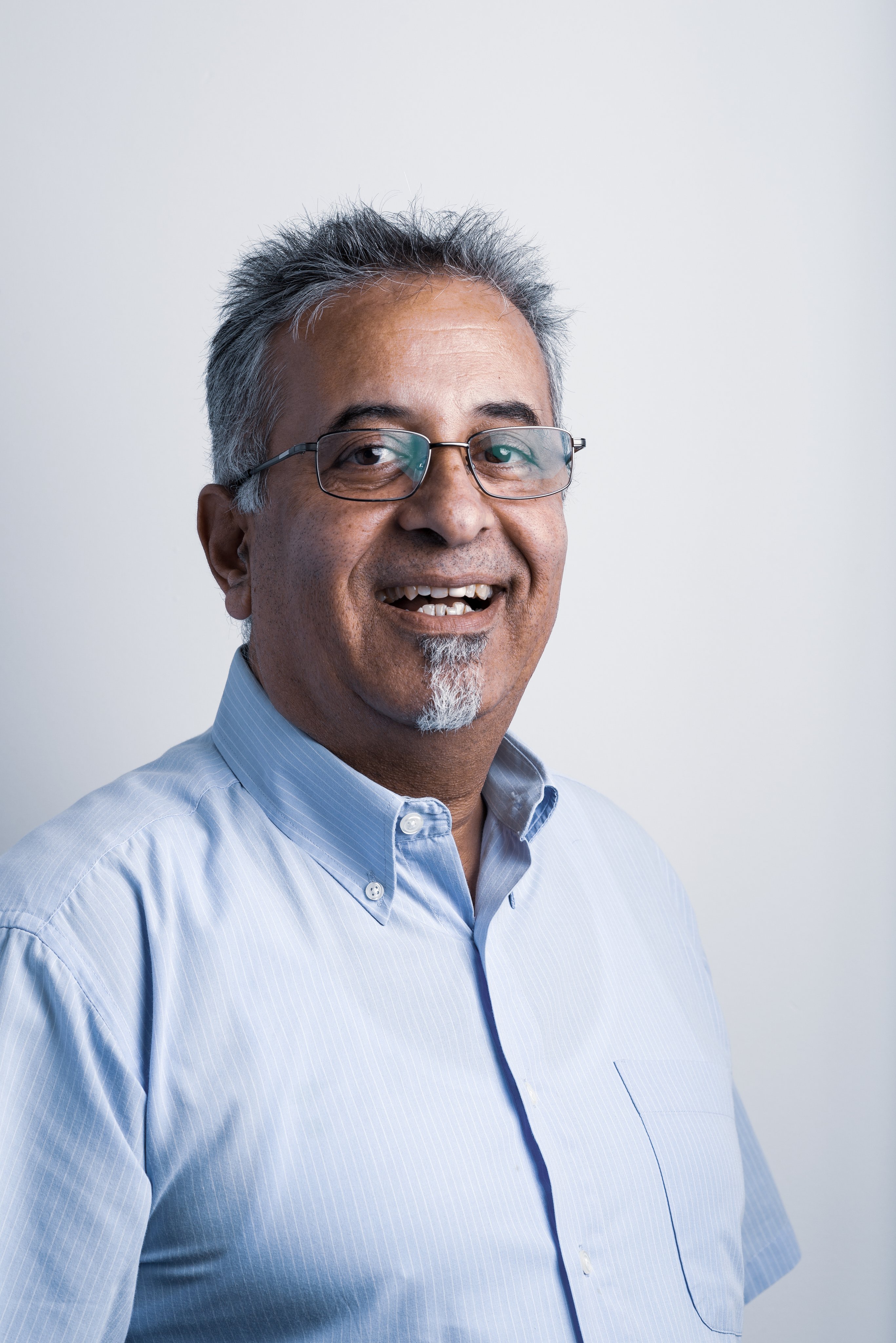 Professional portrait of a smiling Oertli employee wearing glasses and a light blue shirt