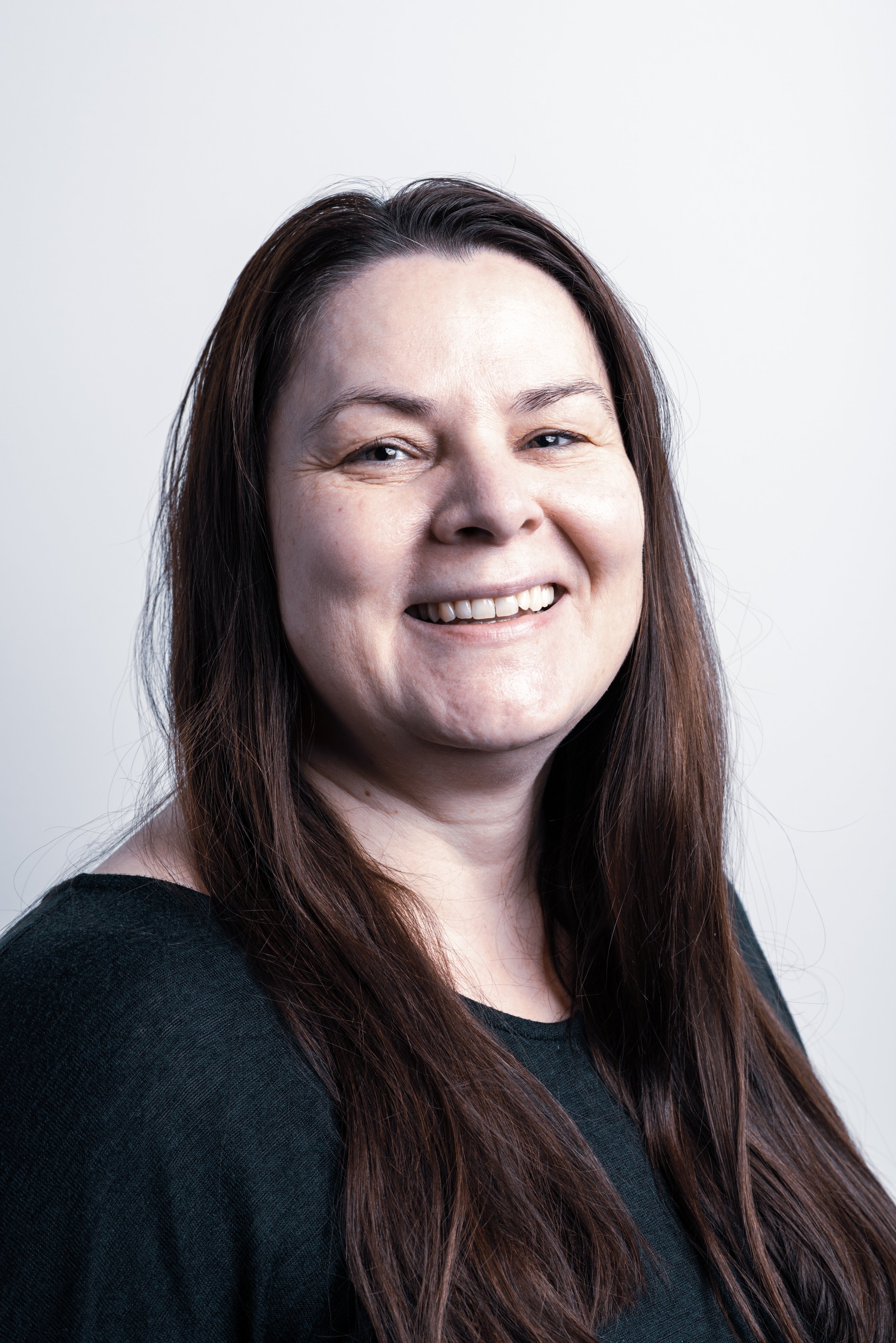 Professional portrait of a smiling Oertli employee with long brown hair
