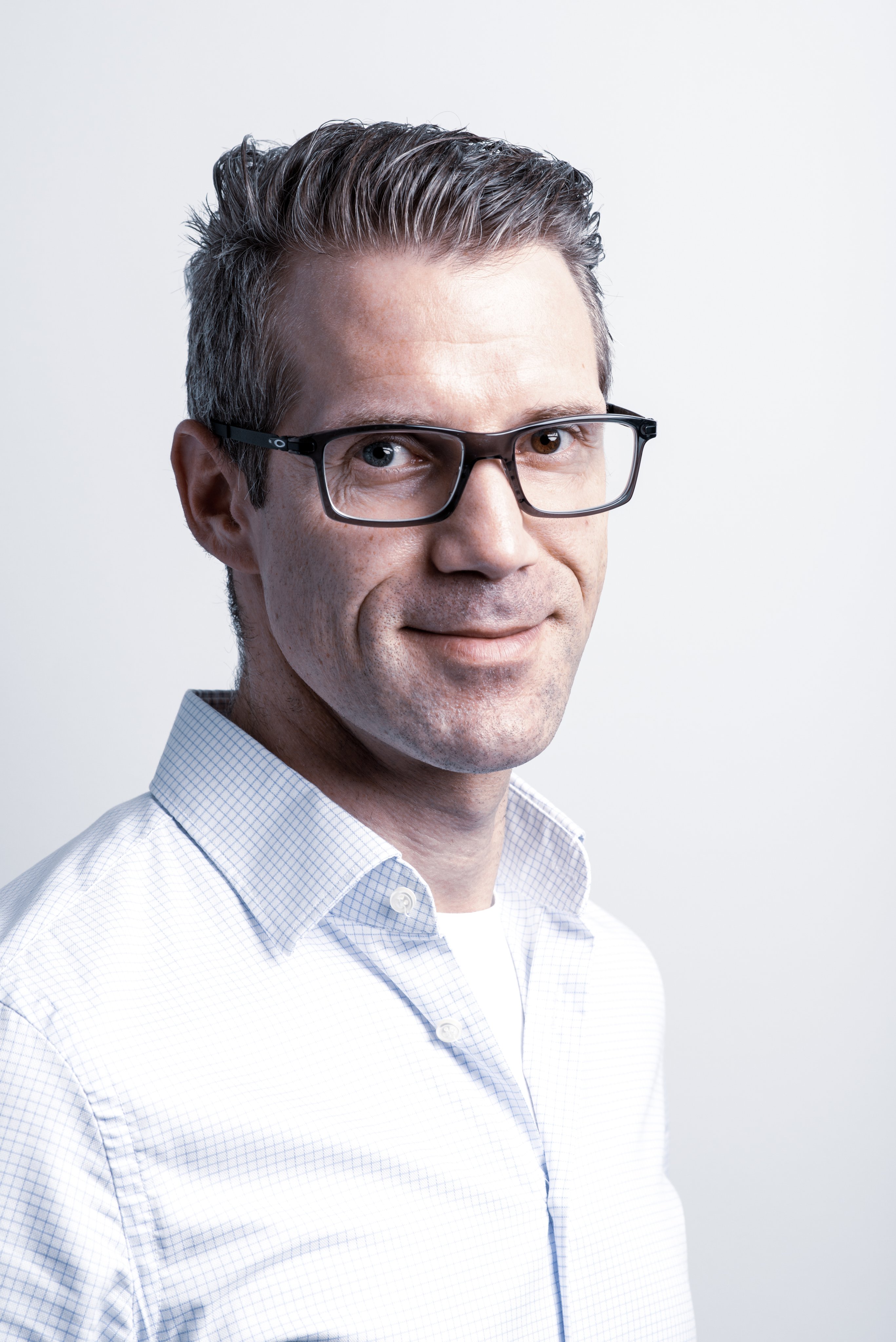 Professional portrait of an Oertli employee wearing glasses and a light blue shirt