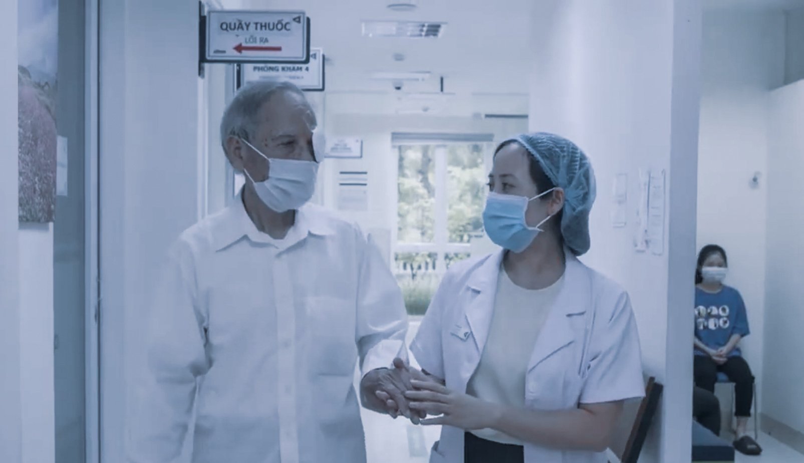 Healthcare professional assisting an elderly patient in a corridor at Alina Eye Hospital