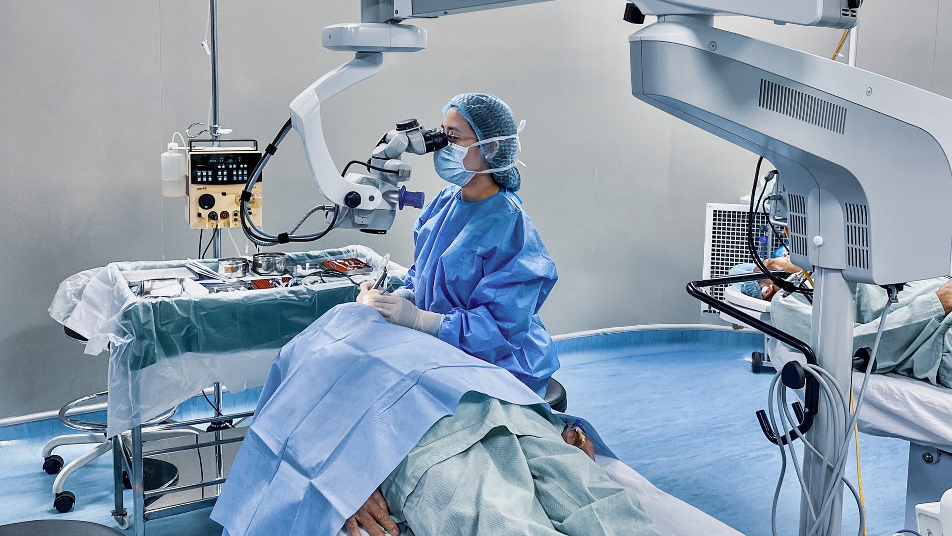 Ophthalmic surgeon performing eye surgery with CataRhex 3 by Oertli in a hospital operating room using a surgical microscope