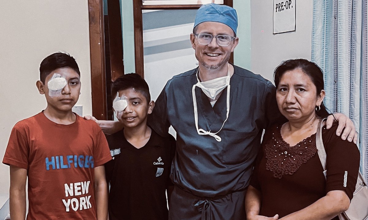 International Eye Institute surgeon with two young patients wearing eye patches and an accompanying adult in a clinic setting