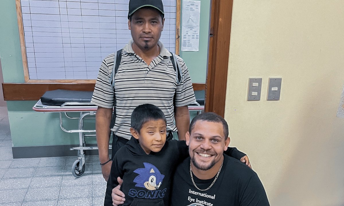 International Eye Institute team member with a child and an adult in a clinic setting