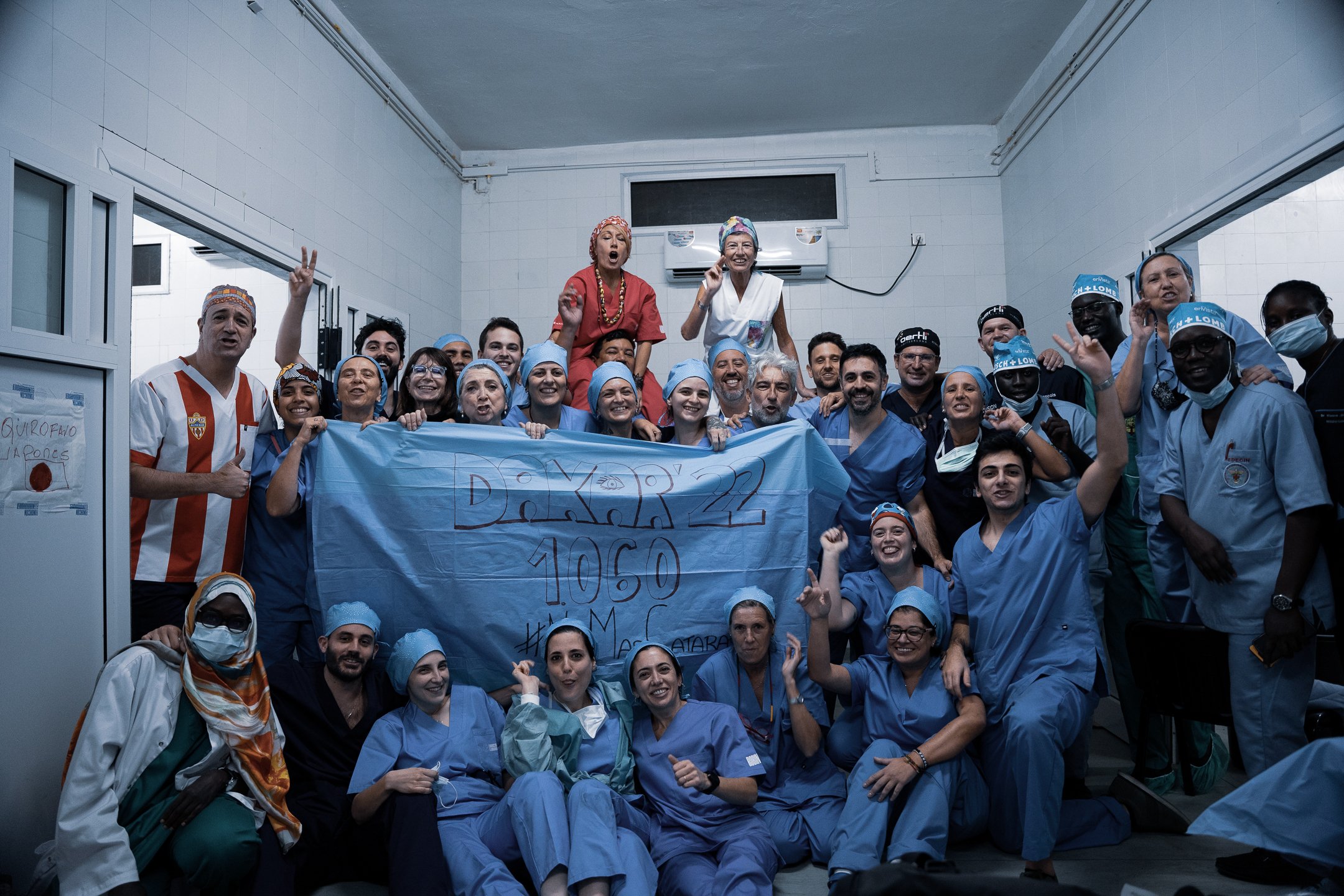 Fundación Elena Barraquer medical team celebrating during an ophthalmic outreach programme, holding a banner marking 1,000 procedures
