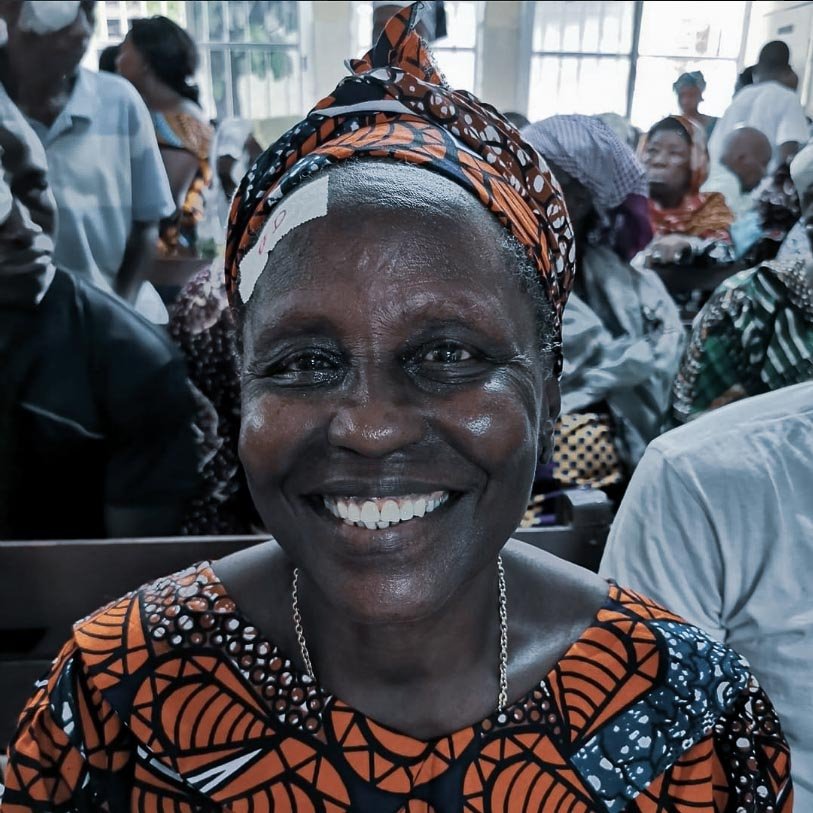 Smiling woman attending an eye care outreach programme, representing the life changing impact of improved access to cataract treatment and vision care
