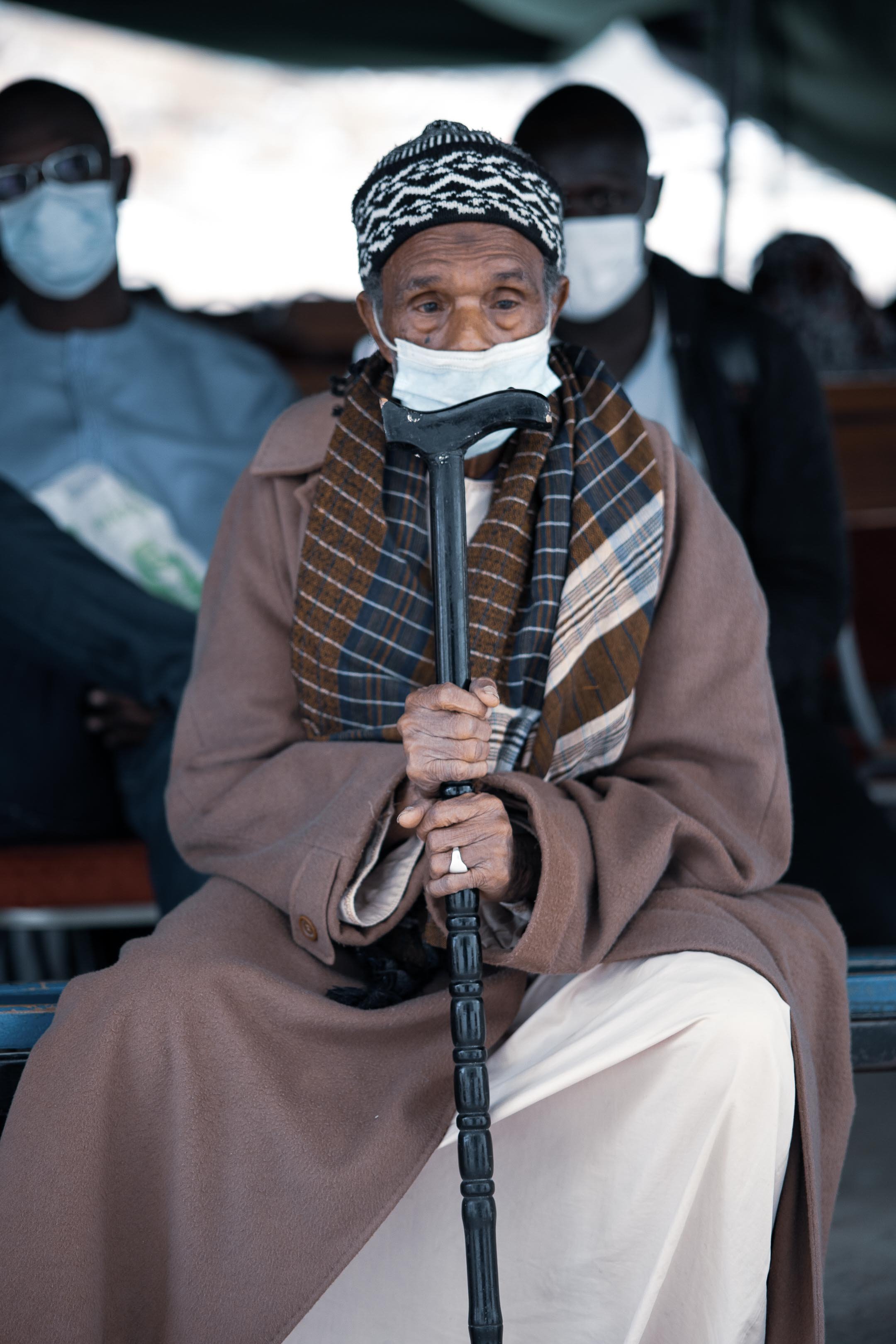 Patient wearing a face mask and holding a cane while waiting during a Fundación Elena Barraquer ophthalmic outreach programme