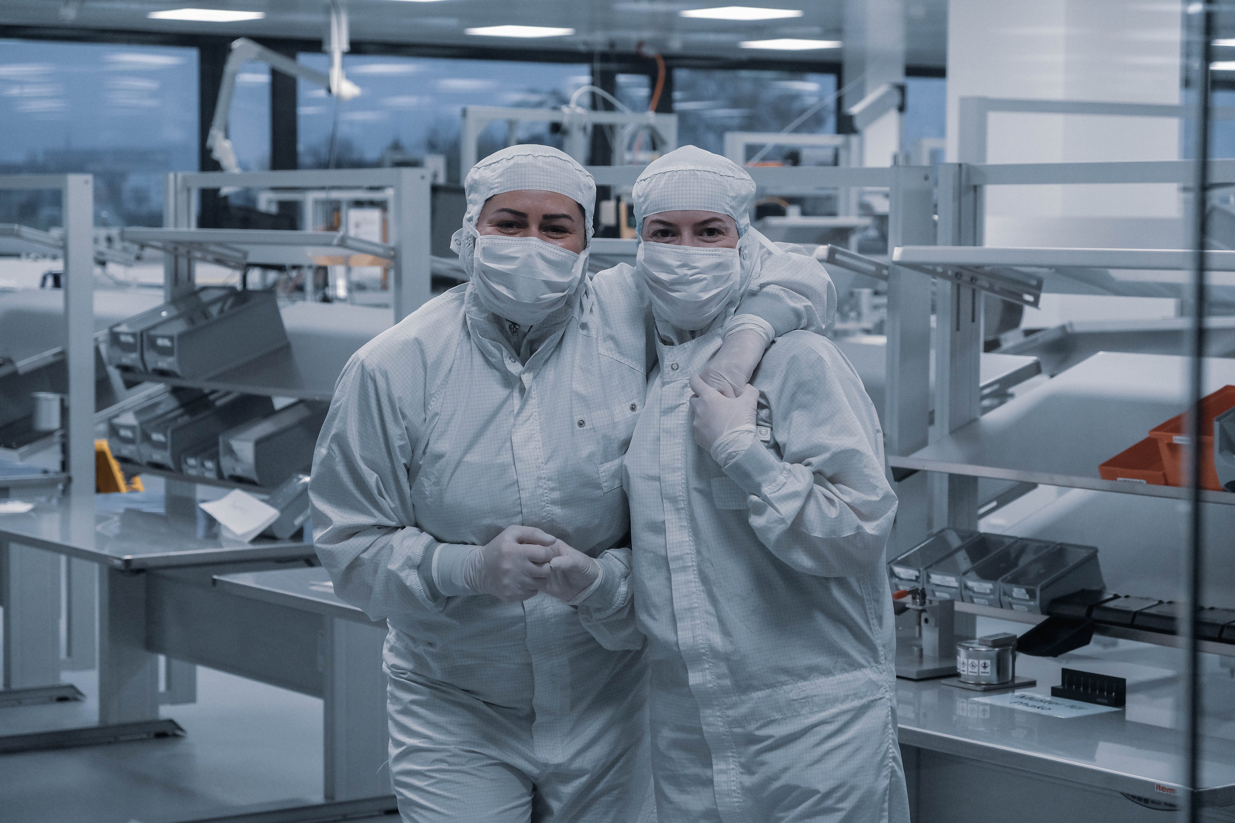 Zwei Mitarbeitende in Reinraumbekleidung und Schutzmasken im Reinraum von Oertli. Sie stehen gemeinsam in der Produktionsumgebung für ophthalmologische Chirurgieprodukte