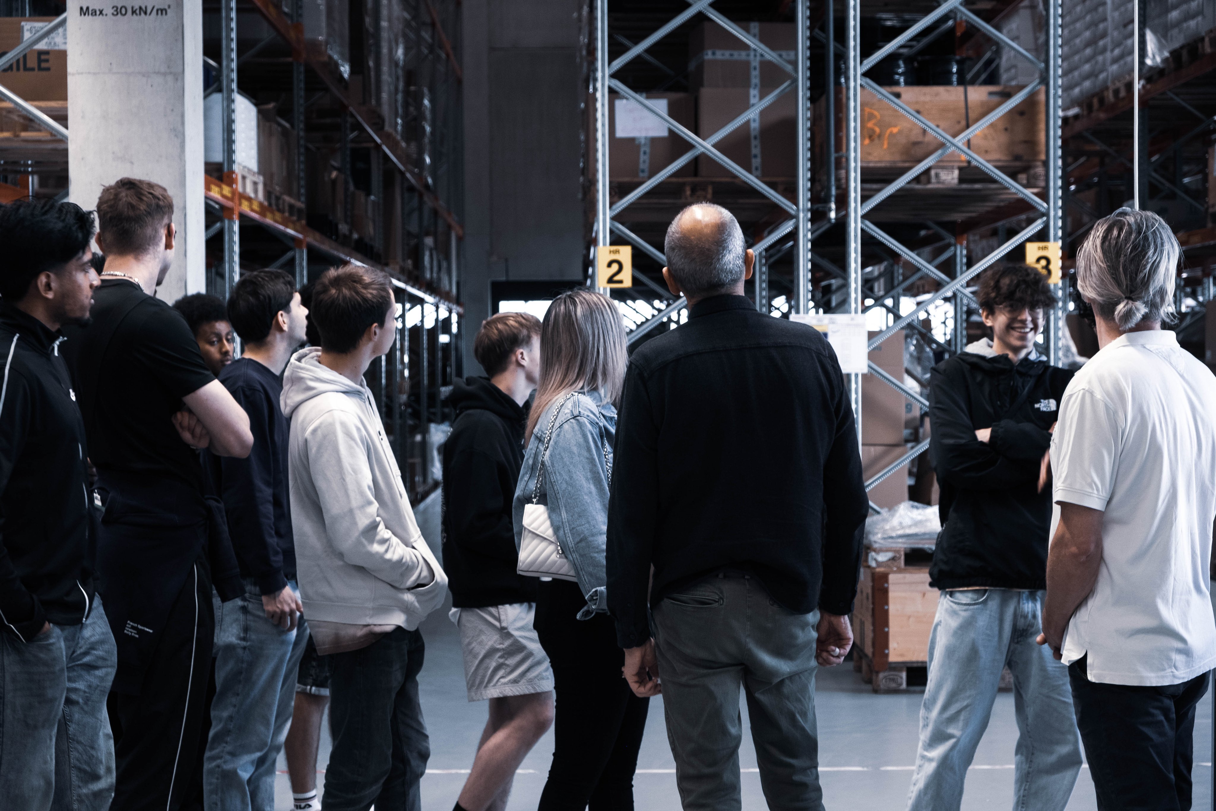 Gruppe von Besuchenden erhält eine Führung durch einen Lagerbereich der Lean Factory