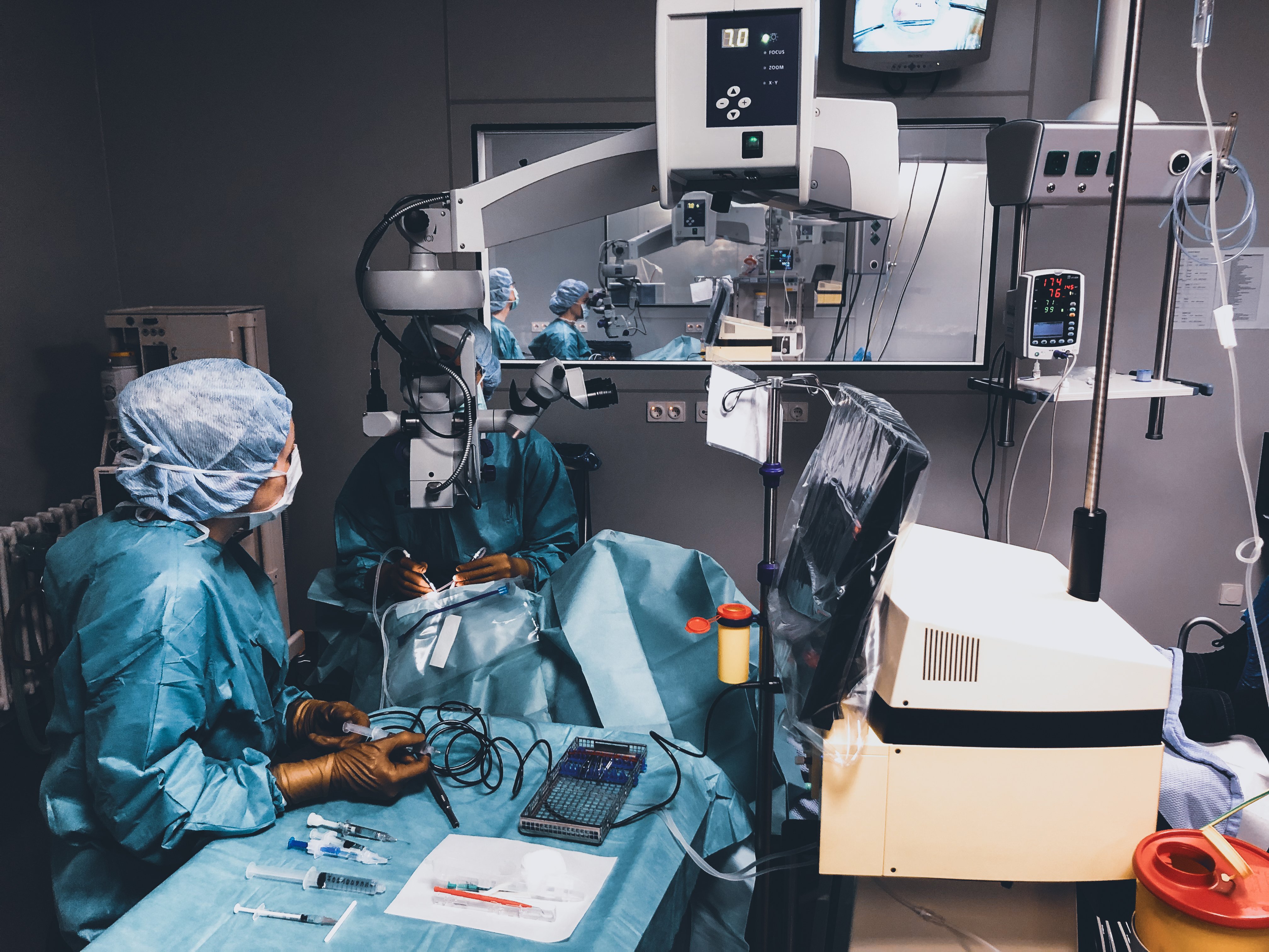 Surgical team performing an ophthalmic procedure in an operating room with microscope and Oertli surgical platform
