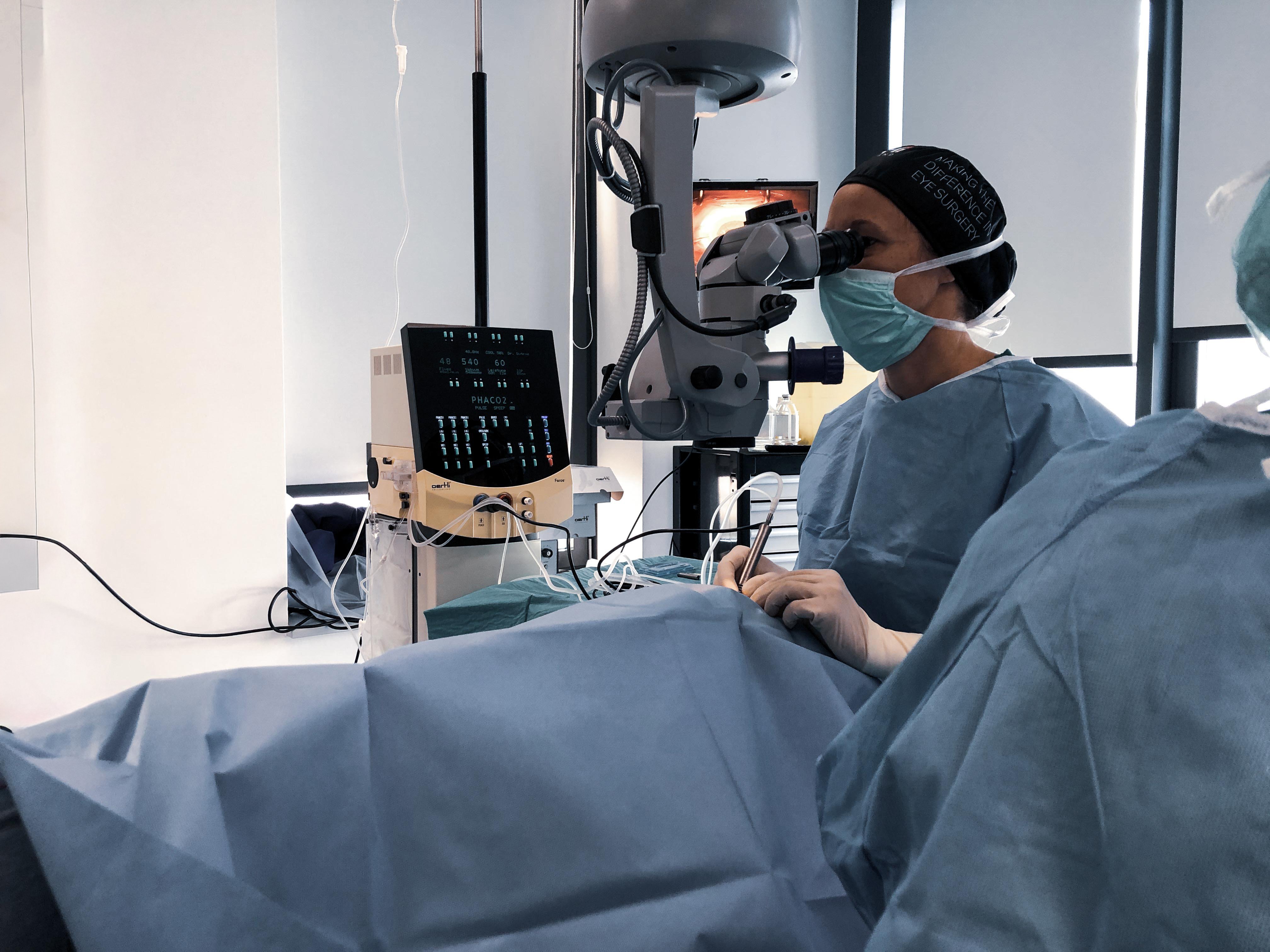 Ophthalmic surgeon performing eye surgery in an operating room with surgical microscope and ophthalmic platform Faros