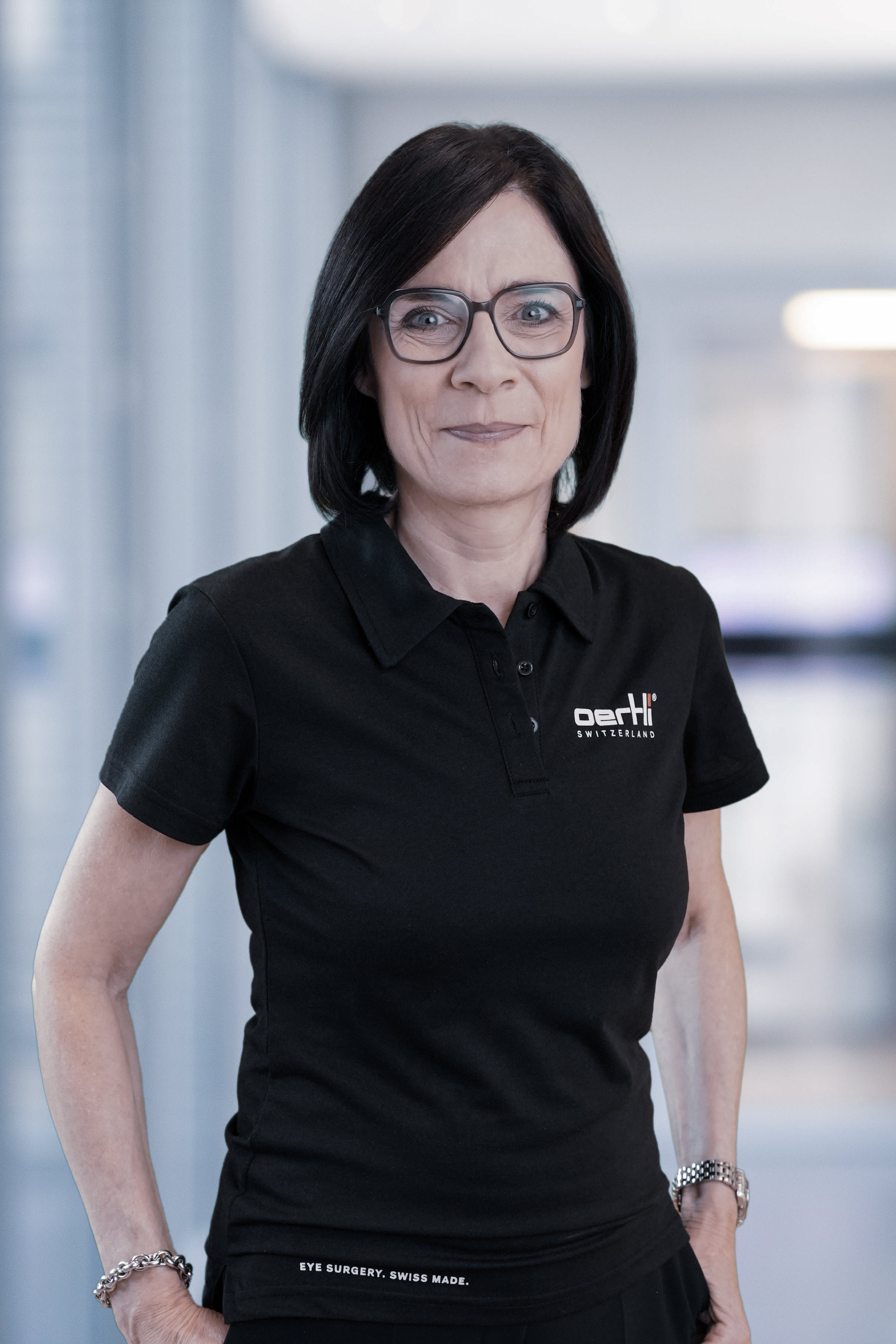 Portrait von Susanne Keller in schwarzem Oertli Poloshirt und Brille im Büro