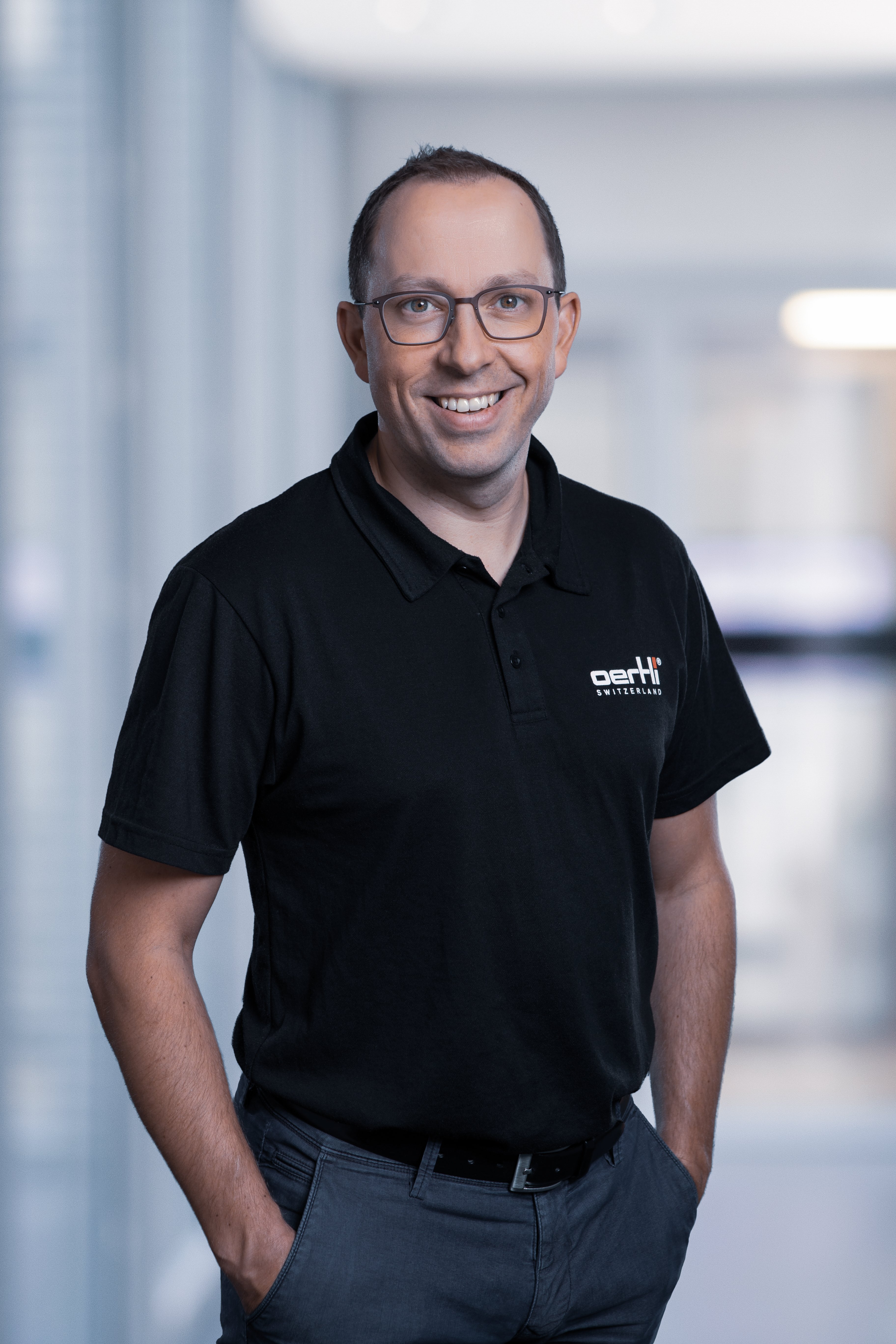 Portrait of  a smiling Thomas Bosshard, CEO of Oertli, wearing a black company polo shirt