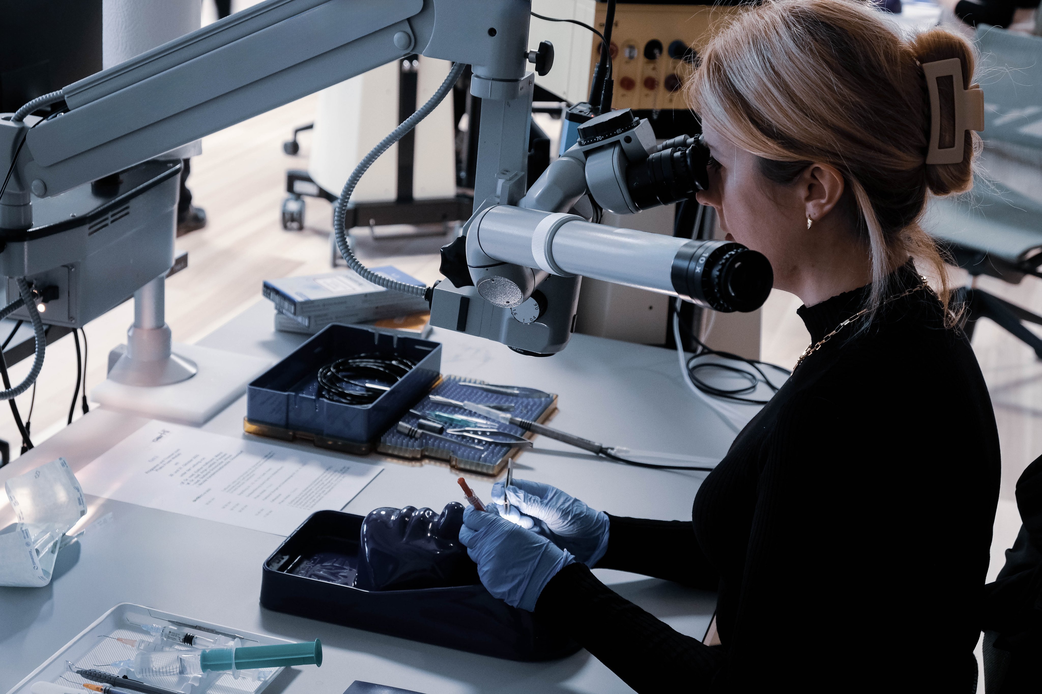 Woman surgeon practising ophthalmic microsurgery under a surgical microscope during a hands on wetlab training session.