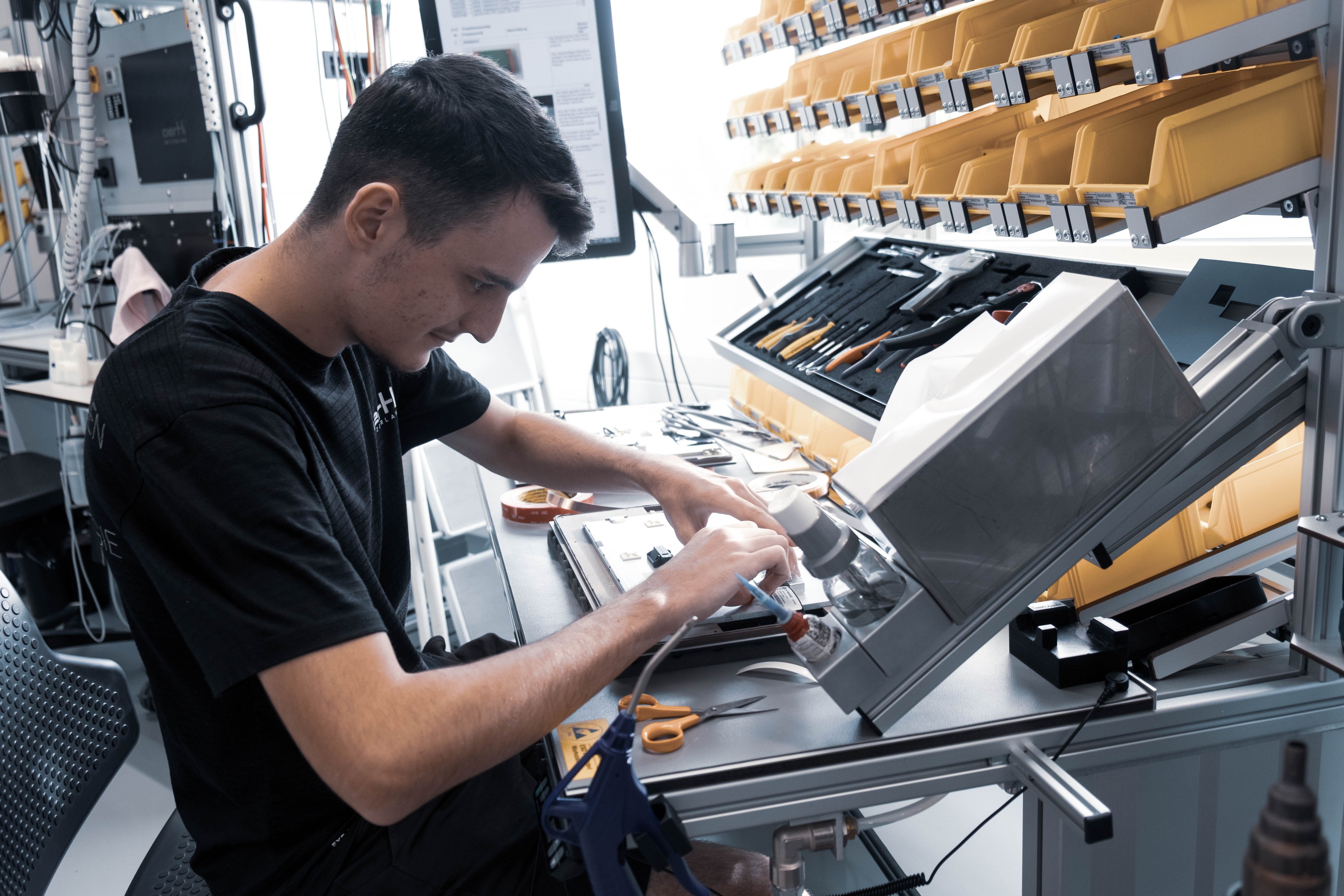 Lernender bei der Montage und Feinbearbeitung eines medizinischen Geräts an einem technischen Arbeitsplatz.