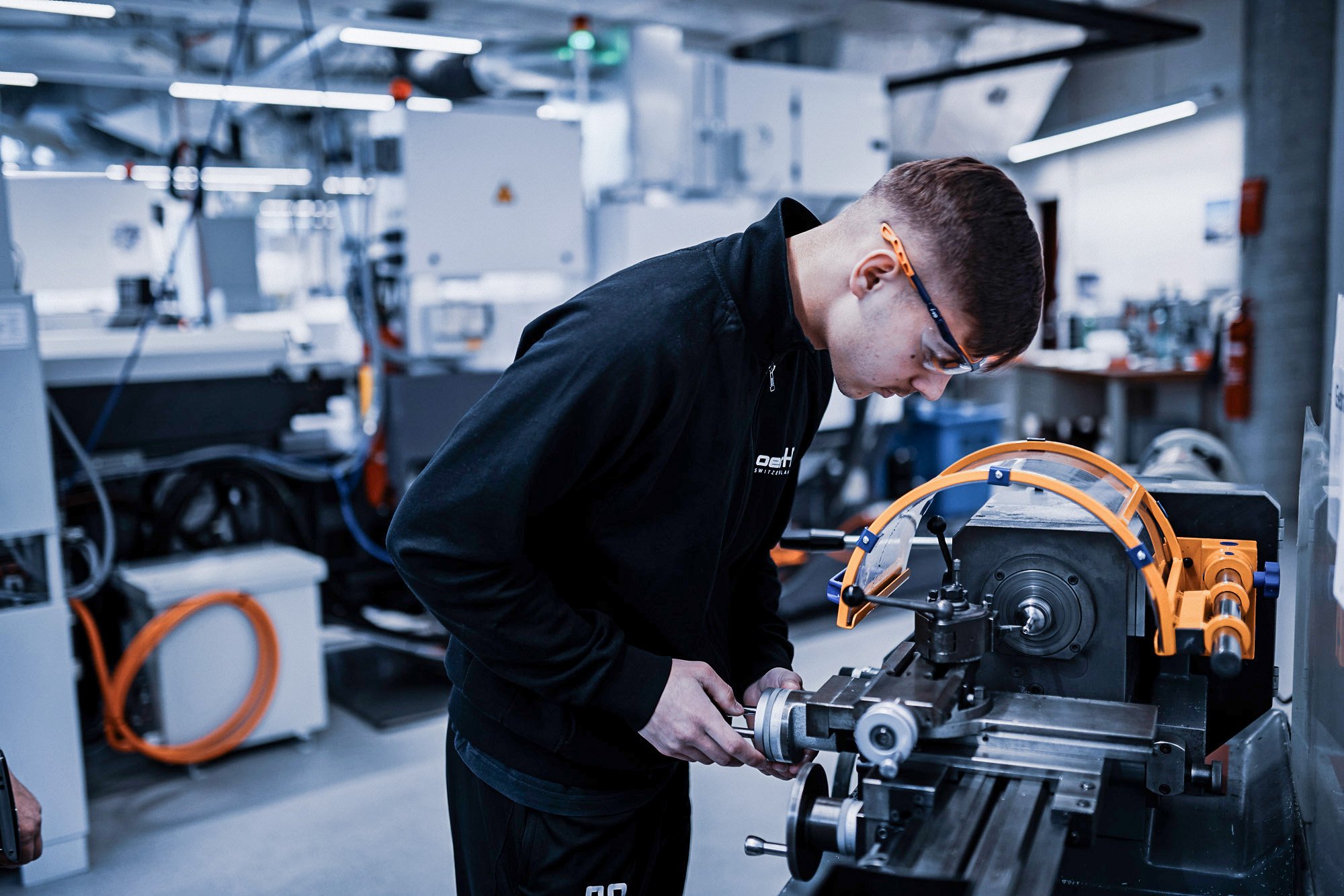 Mitarbeitender bedient eine Drehmaschine in einer modernen Produktionshalle