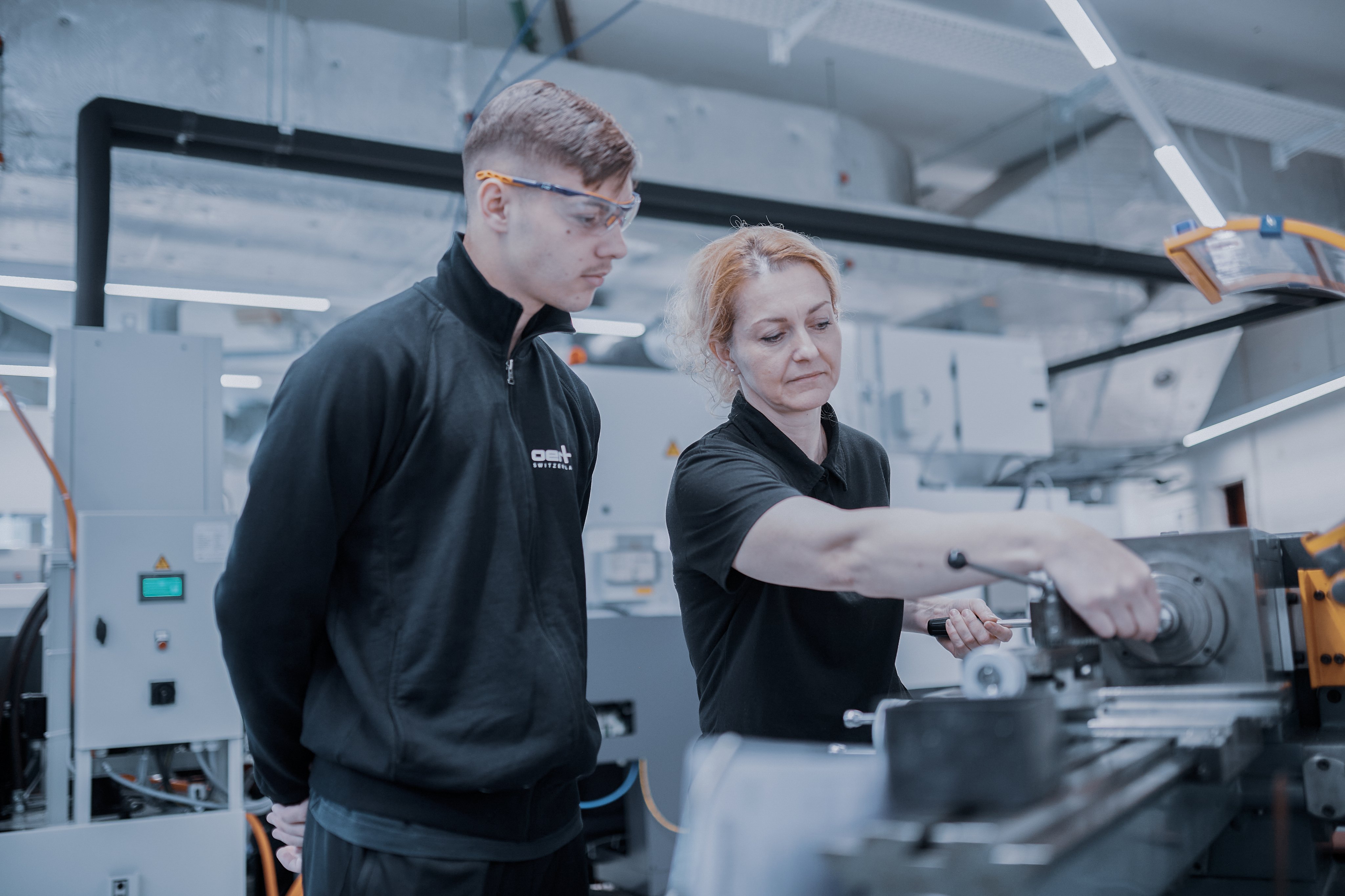 Oertli apprentice receiving hands-on training at a production machine in the manufacturing area