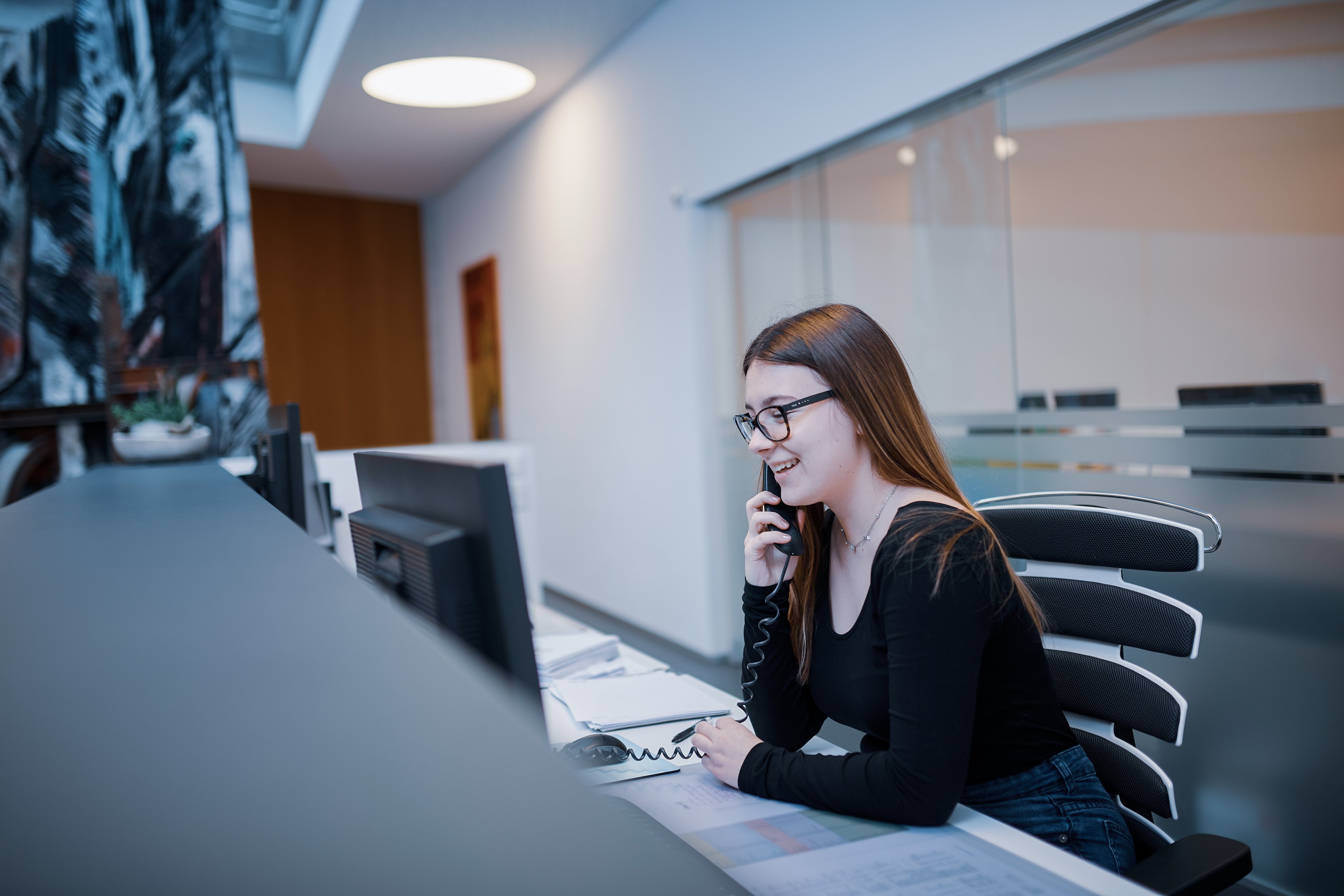 Mitarbeitende telefoniert an einem Arbeitsplatz im Büro