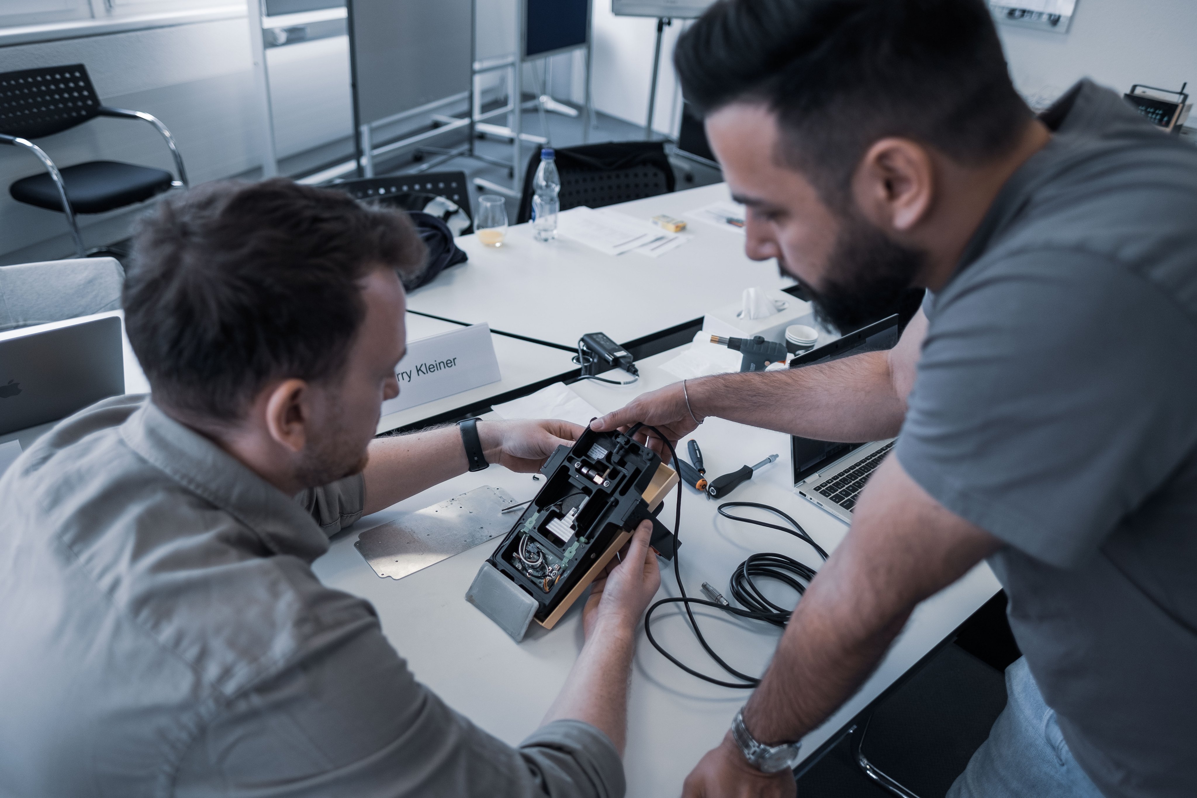 Participants inspect an ophthalmic device module during an Oertli international service training session