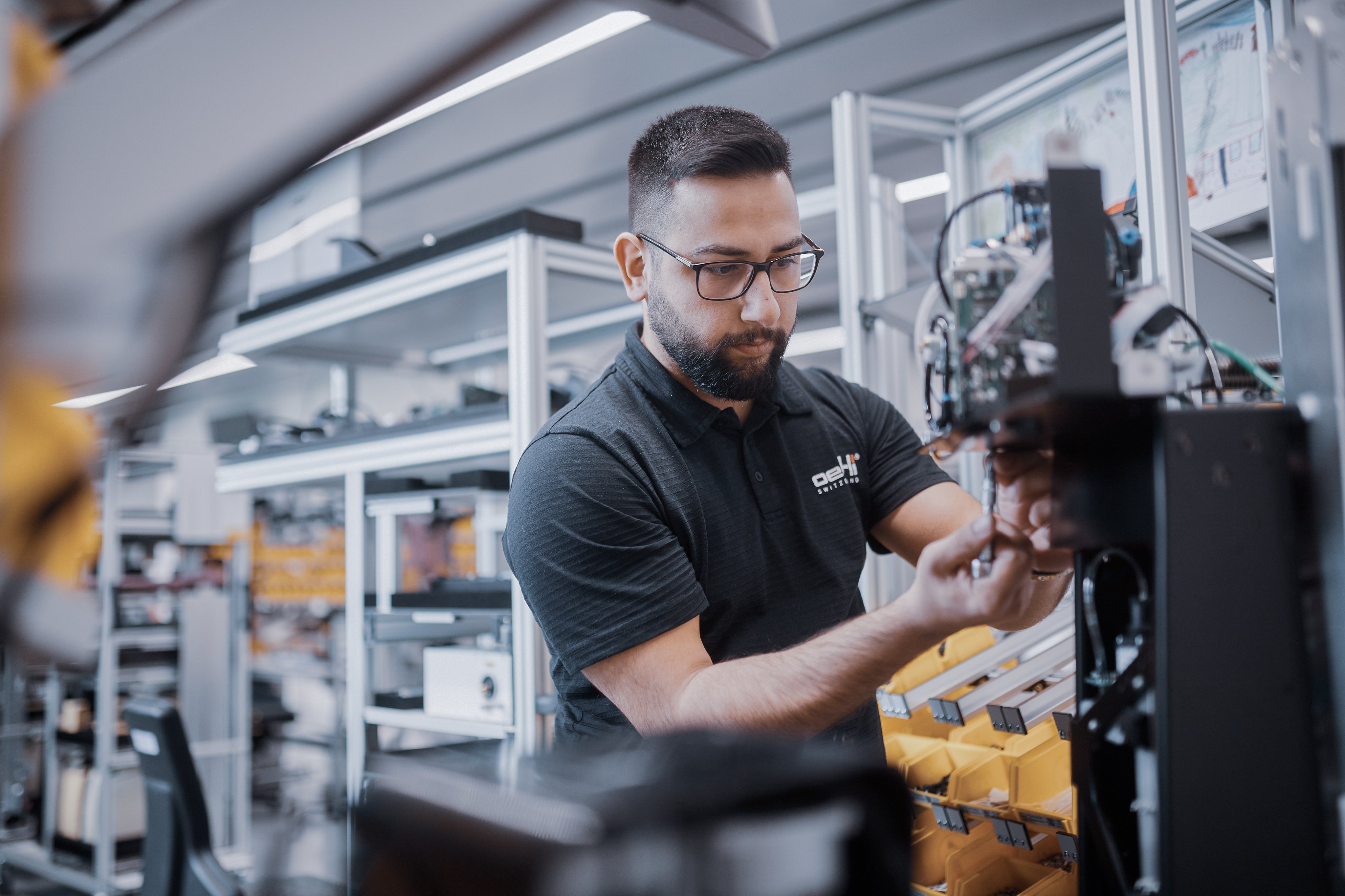 Ein Oertli Mitarbeiter mit Brille bei einer technischen Arbeit an einer Maschine in der Opthalmologie