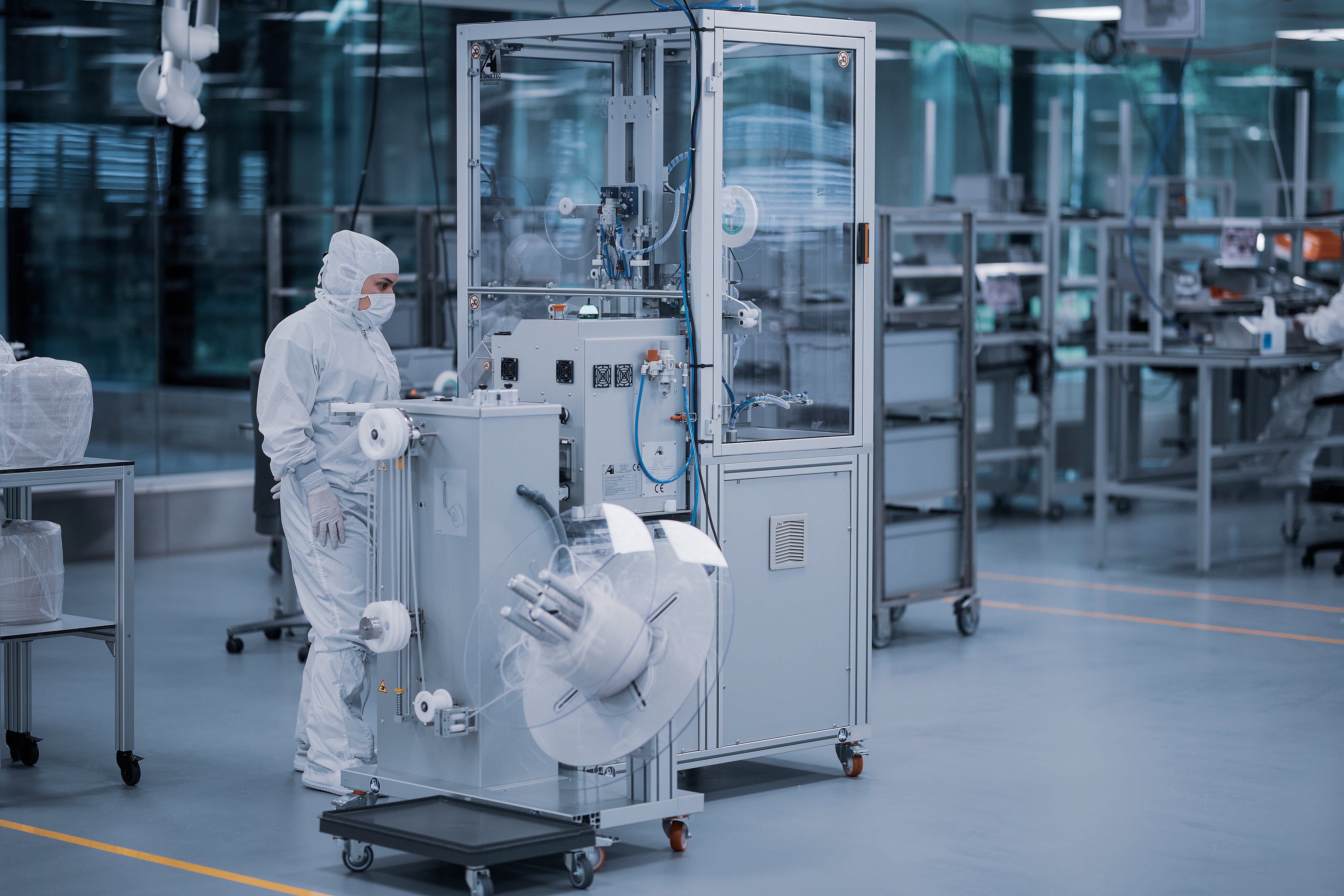 Employee operating an automated manufacturing system in a cleanroom for medical device production
