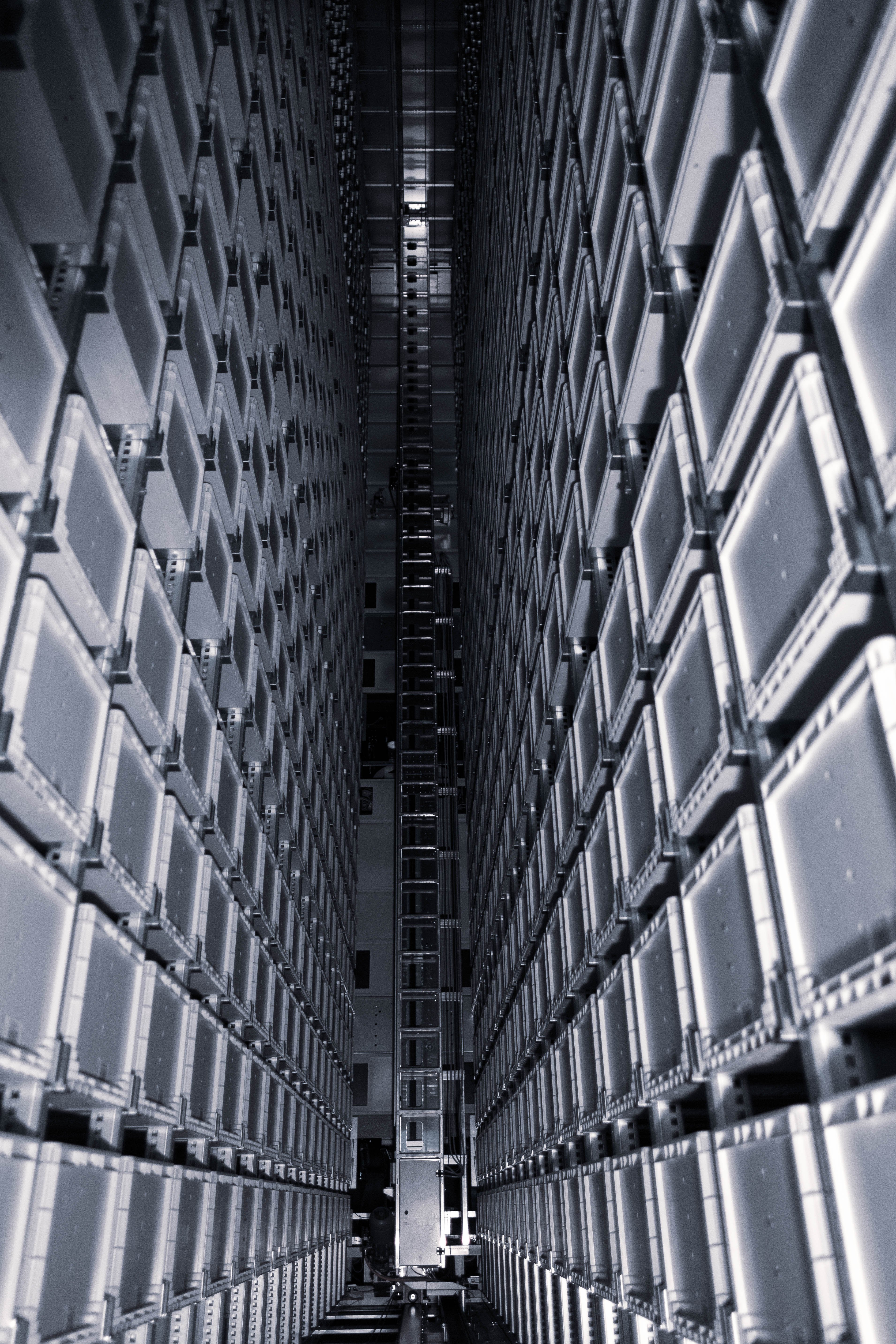 View inside an automated high-bay warehouse with tall storage racks and container bins extending vertically across multiple levels