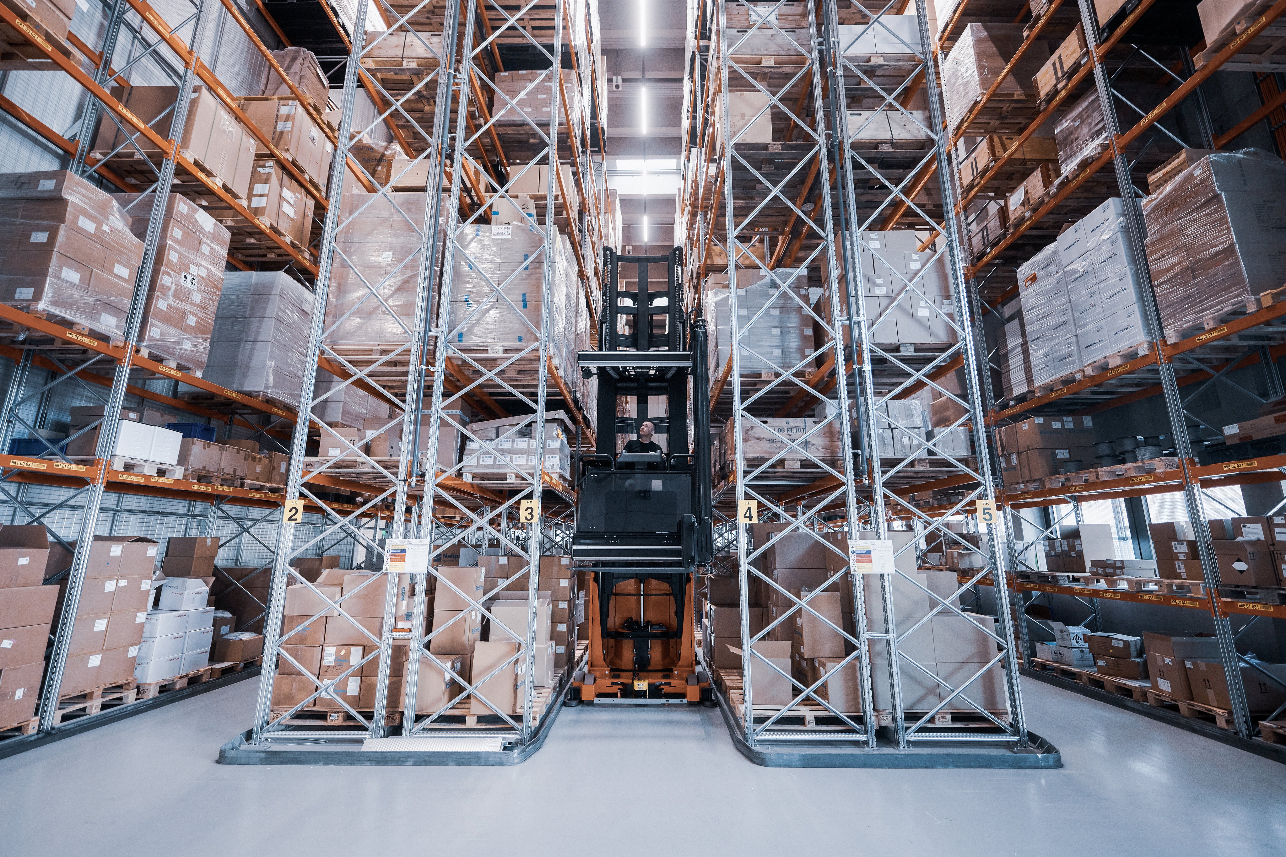 Forklift operating between high storage racks in the Oertli logistics warehouse