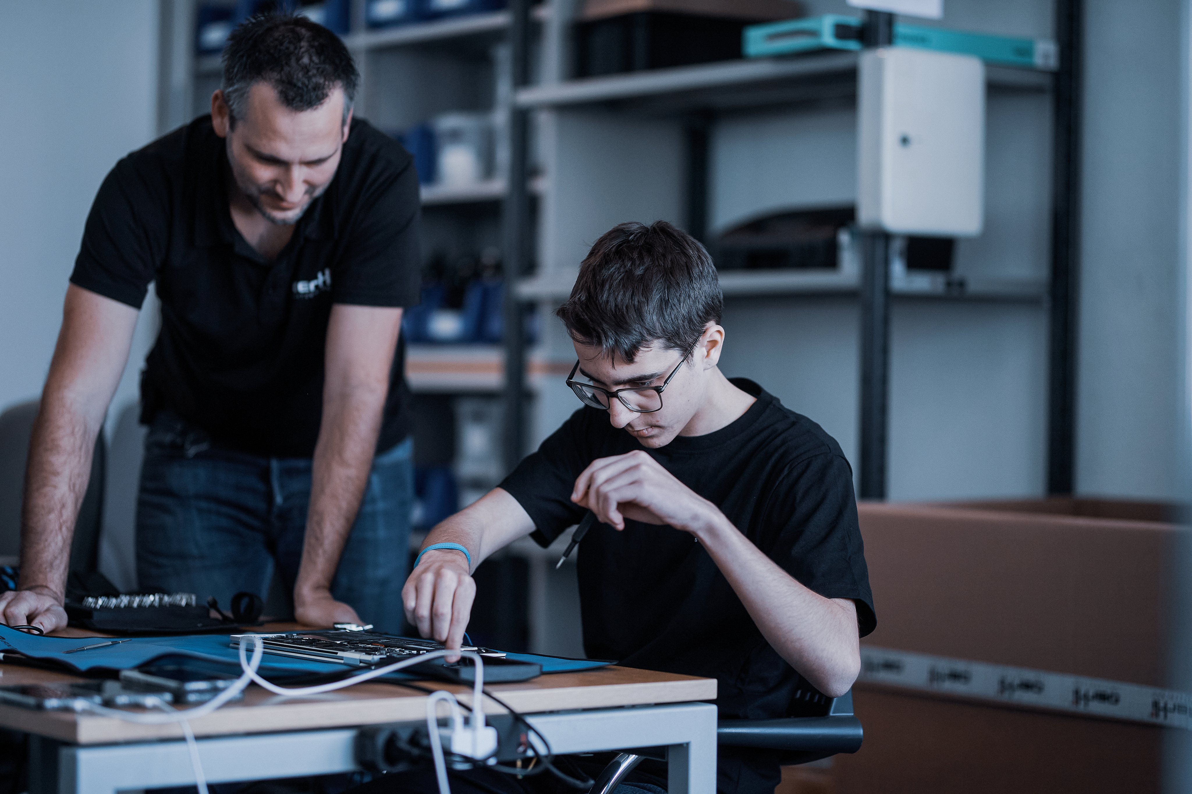 Lehrmeister unterstützt Lernenden bei der Arbeit an elektronischen Komponenten