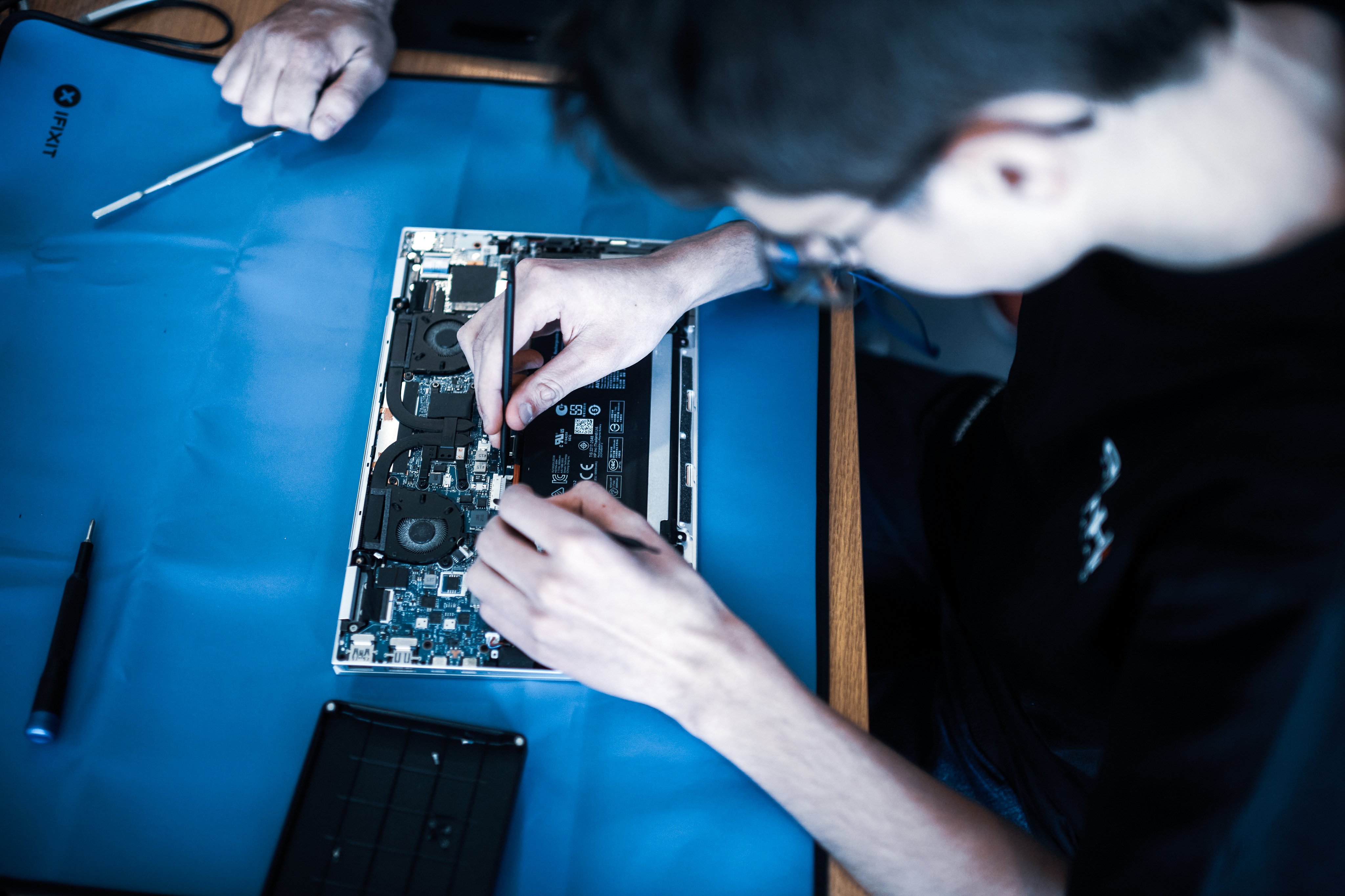 IT Lernender repariert ein elektronisches Gerät mit seinen Händen