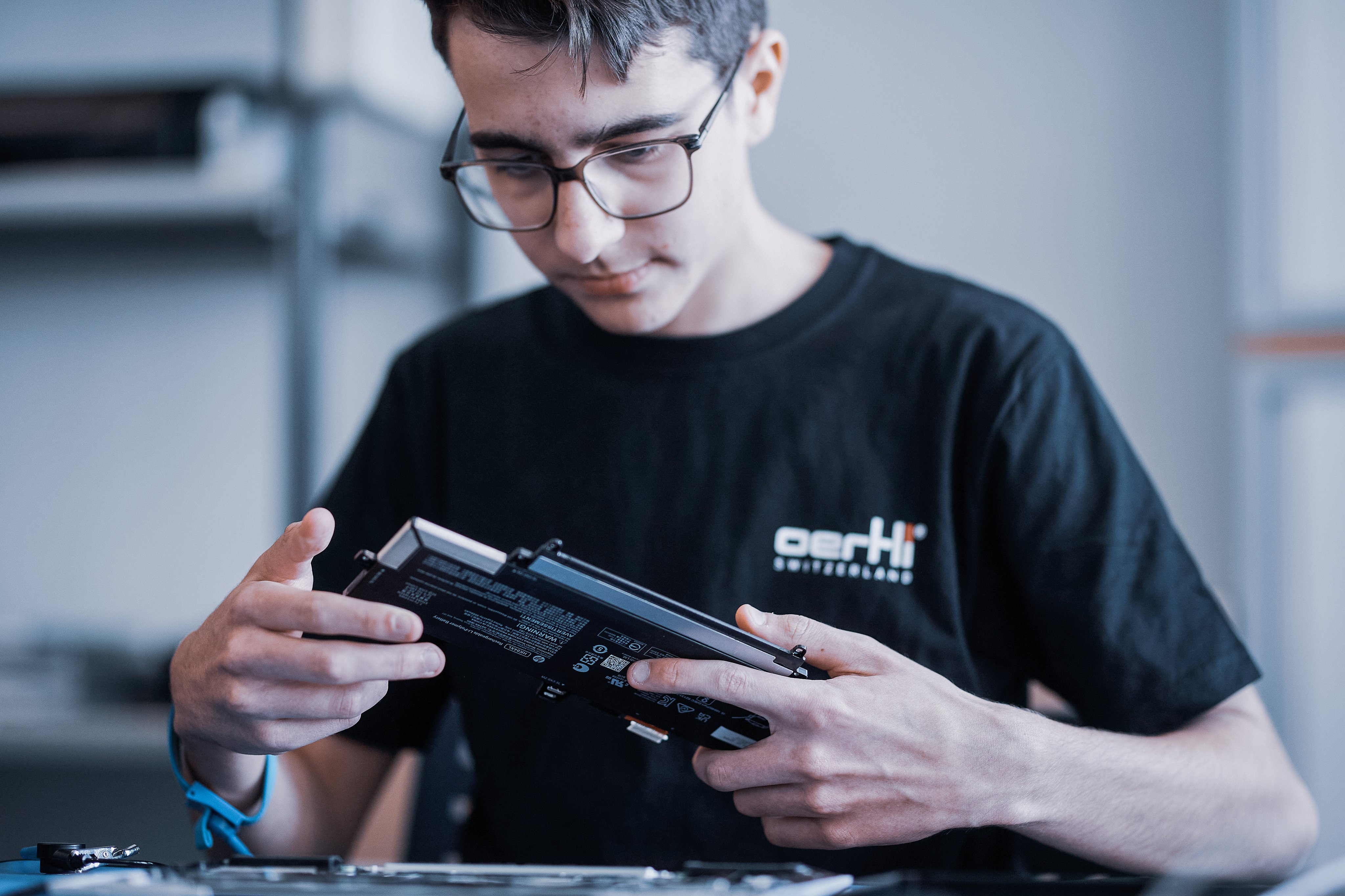 Lehrling prüft eine elektronische Komponente an einem Arbeitsplatz