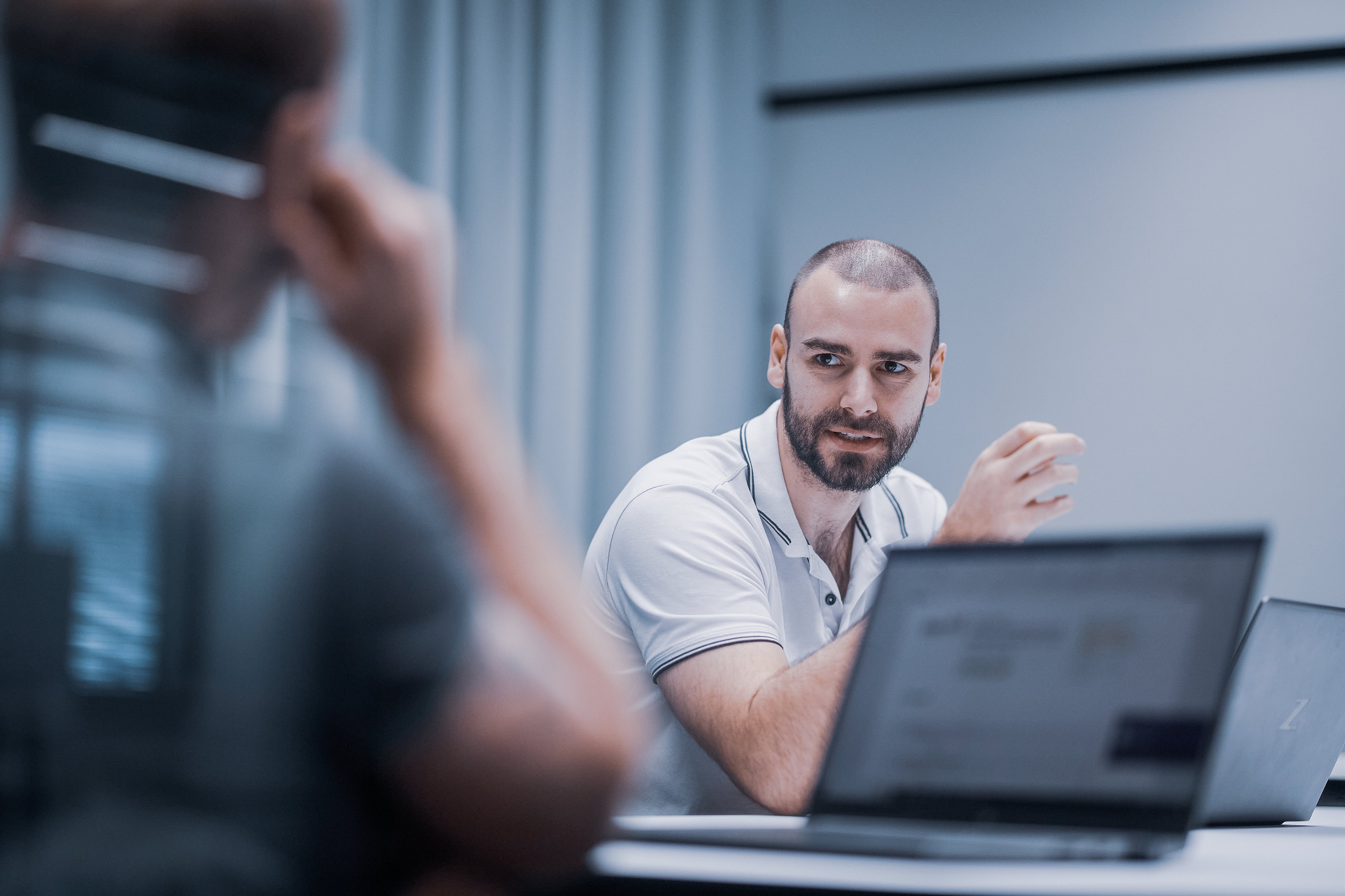 Oertli employee in a meeting room discussing a topic with colleagues and laptops