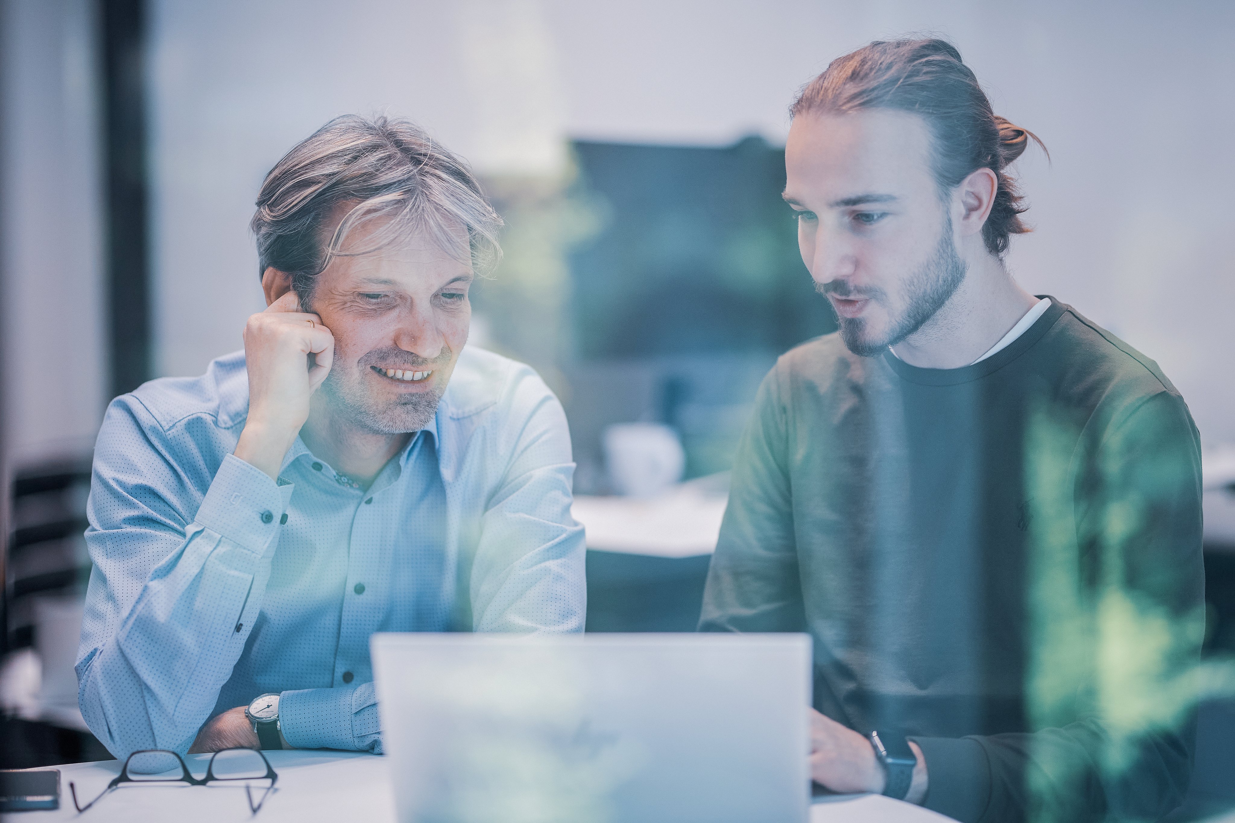 Two Oertli employees discussing work at a laptop in an office setting