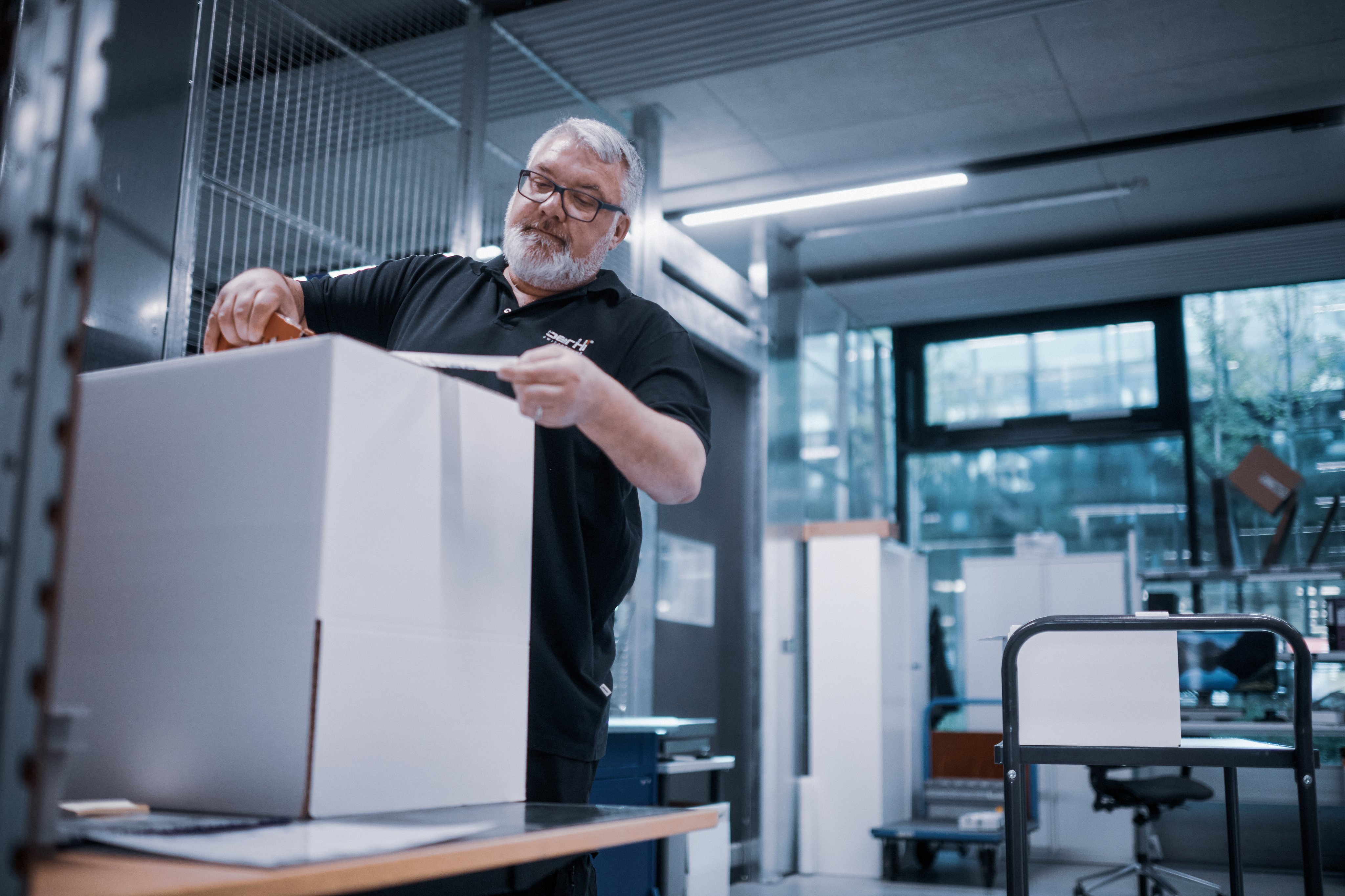Oertli employee packing a shipping box in the logistics area