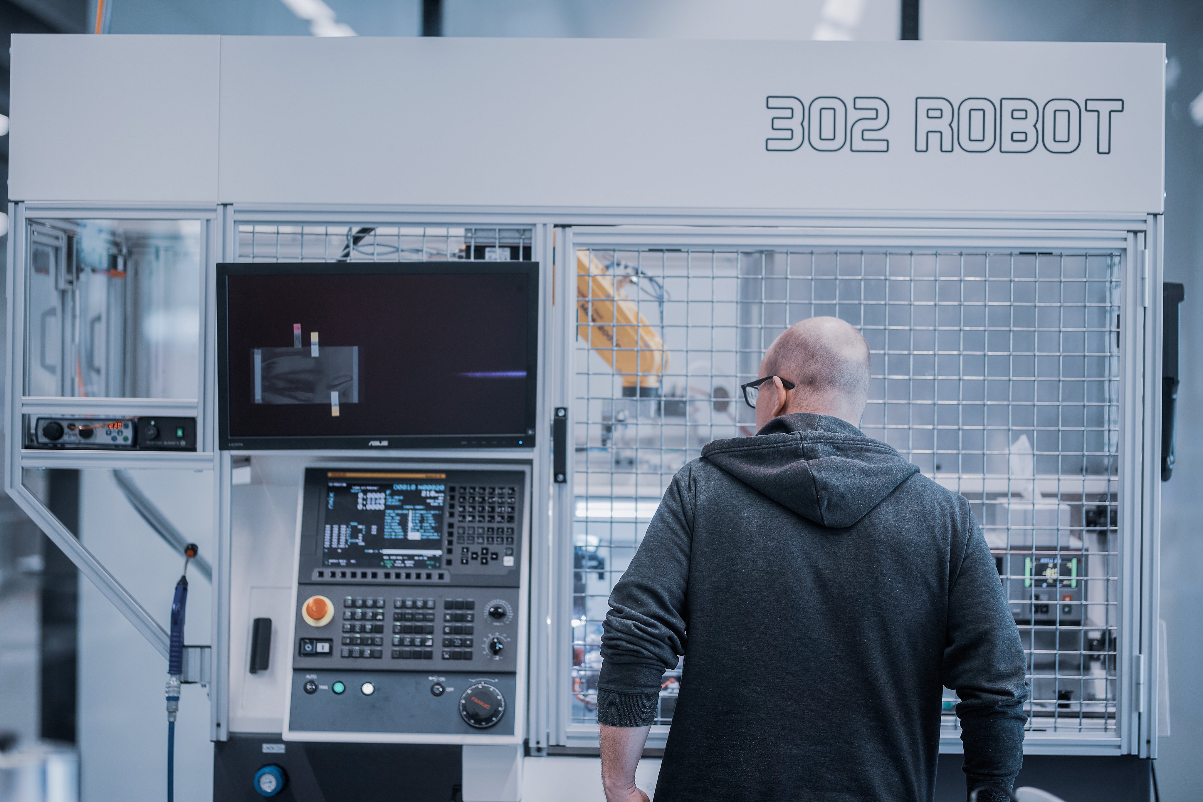 Mitarbeitender bei der Bedienung einer automatisierten Fertigungsanlage in der Produktion.