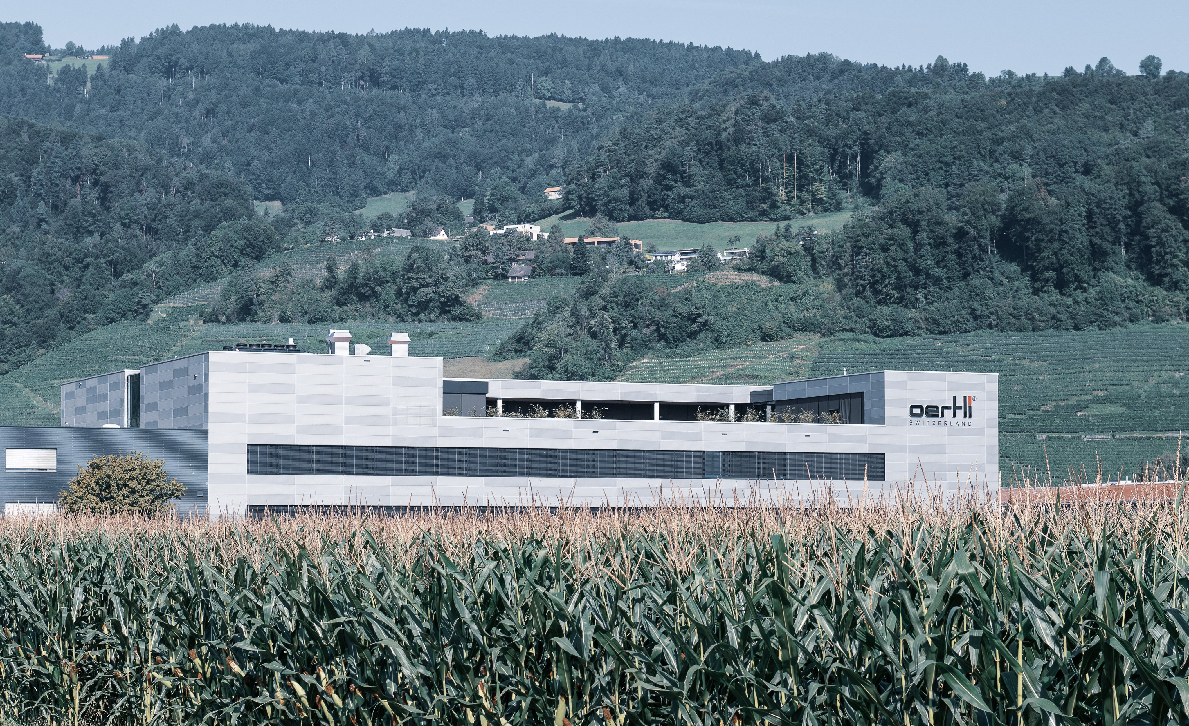 Oertli Lean Factory building surrounded by meadow and hillside landscape