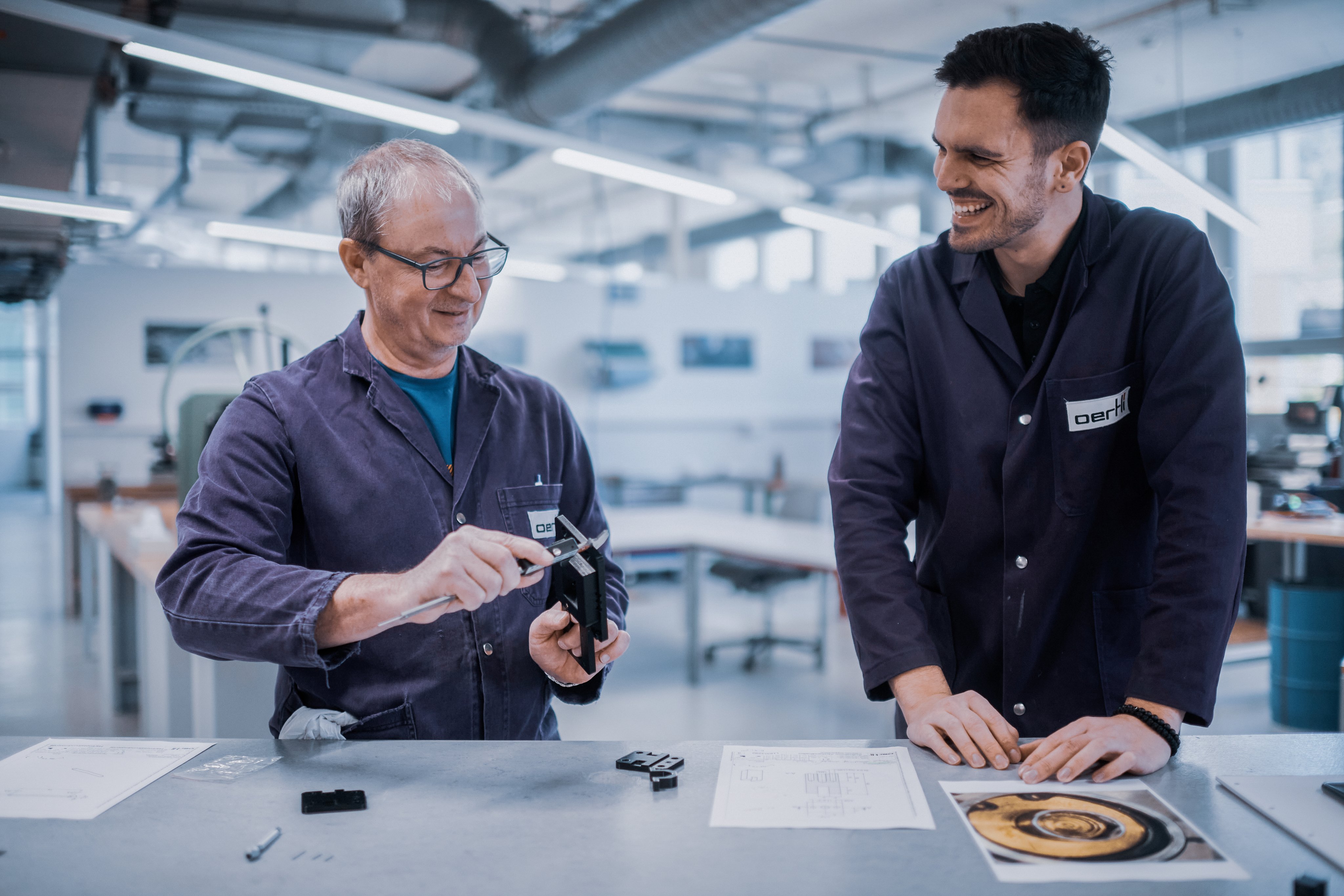 Zwei Mitarbeitende prüfen gemeinsam ein Bauteil und arbeiten an einem Prototypen in der Entwicklungswerkstatt