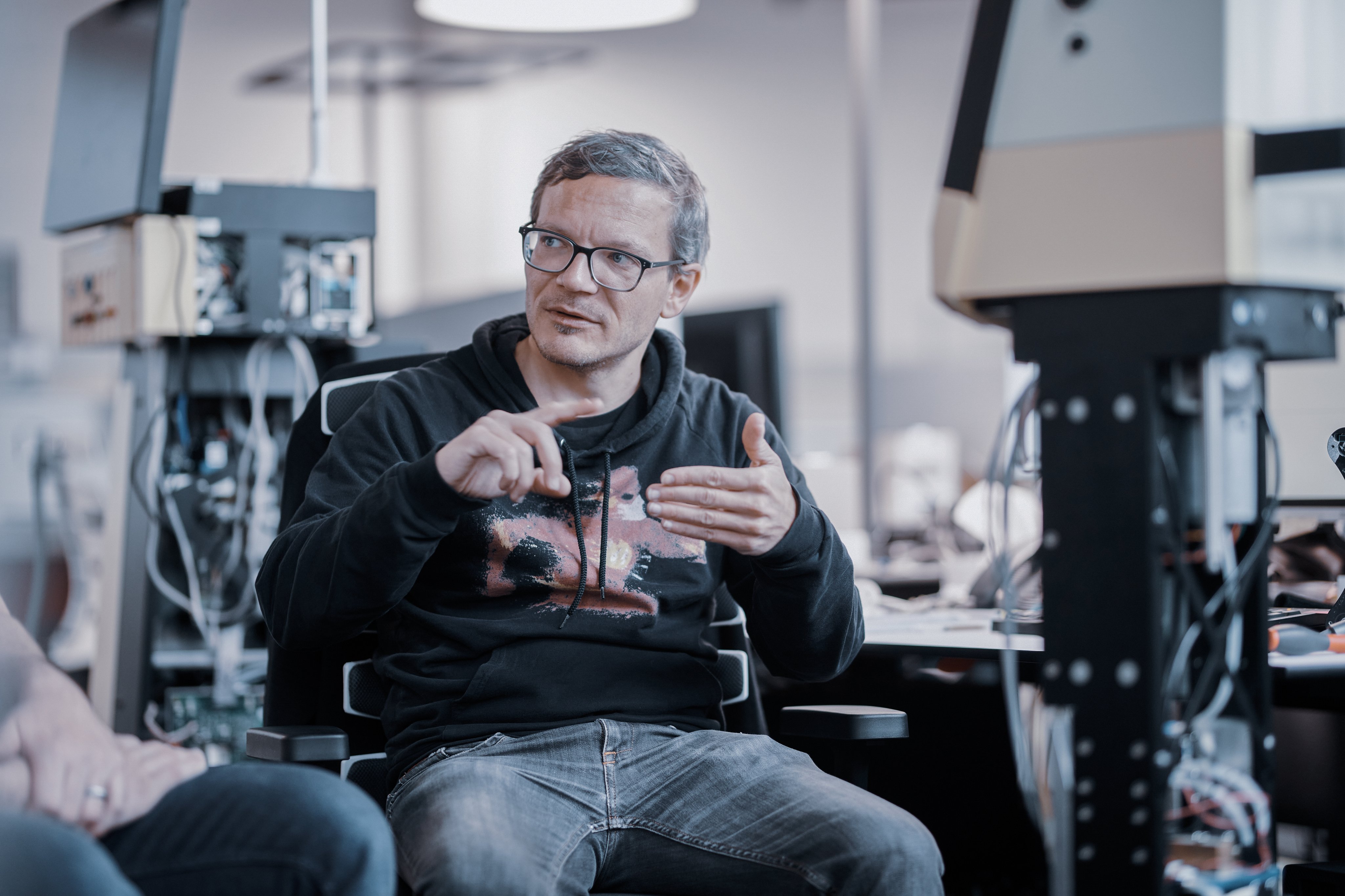 Mitarbeiter aus Forschung und Entwicklung erklärt technische Zusammenhänge während eines Gesprächs zwischen Entwicklungsarbeitsplätzen und Prototypensystemen