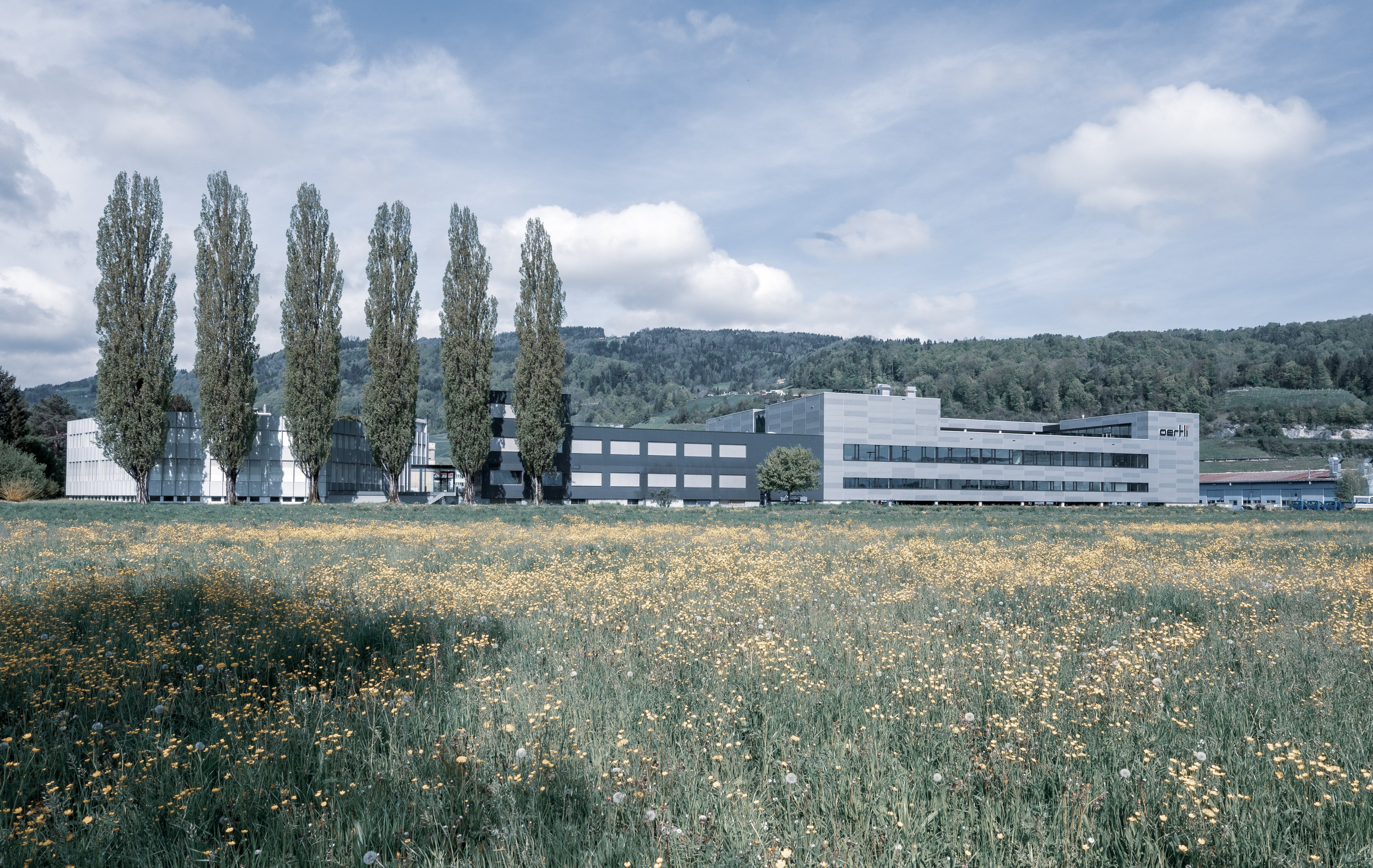 frontal view of the oertli head quarter in berneck, switzerland. Surrounded by green meadows and hills