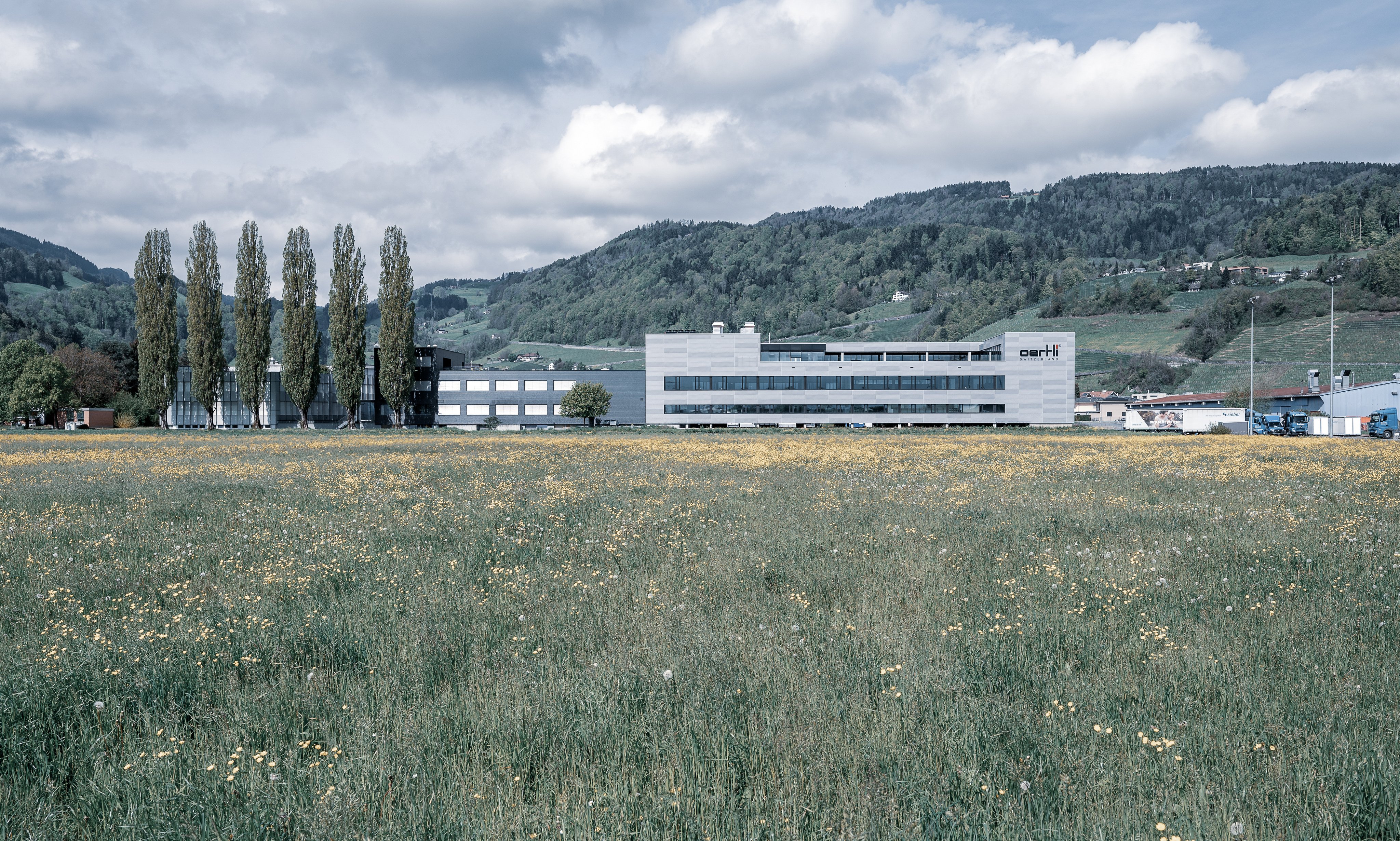 Oertli Lean Factory building surrounded by meadow and hillside landscape
