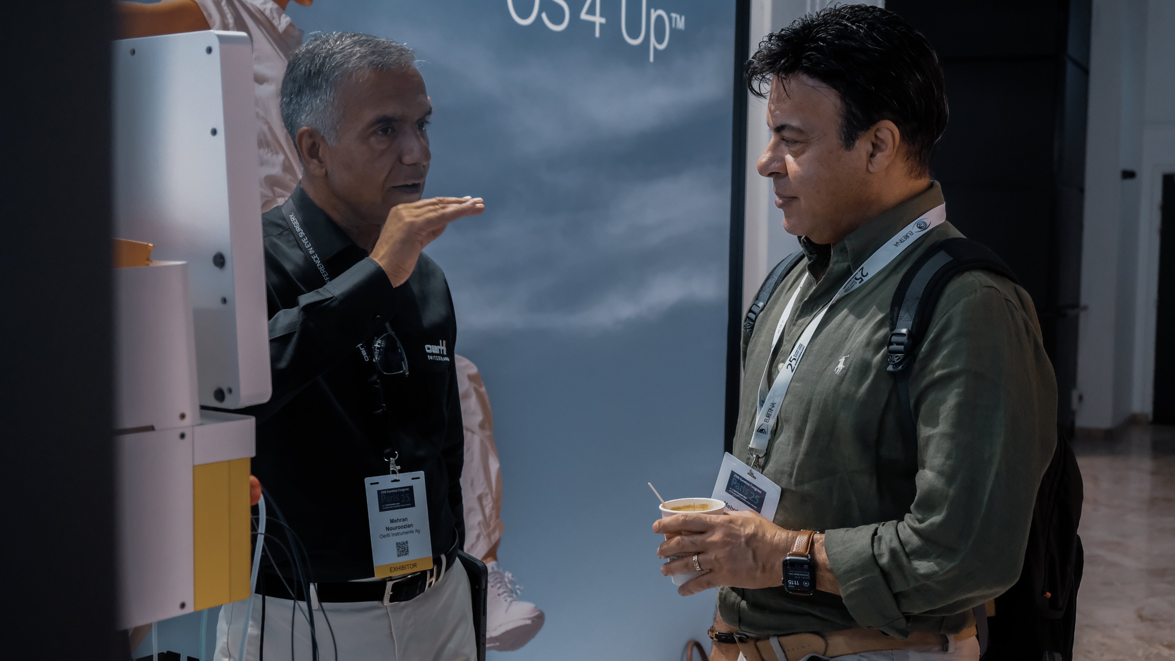 Oertli representative speaking with a visitor at Euretina 2025 in front of an OS 4 Up display
