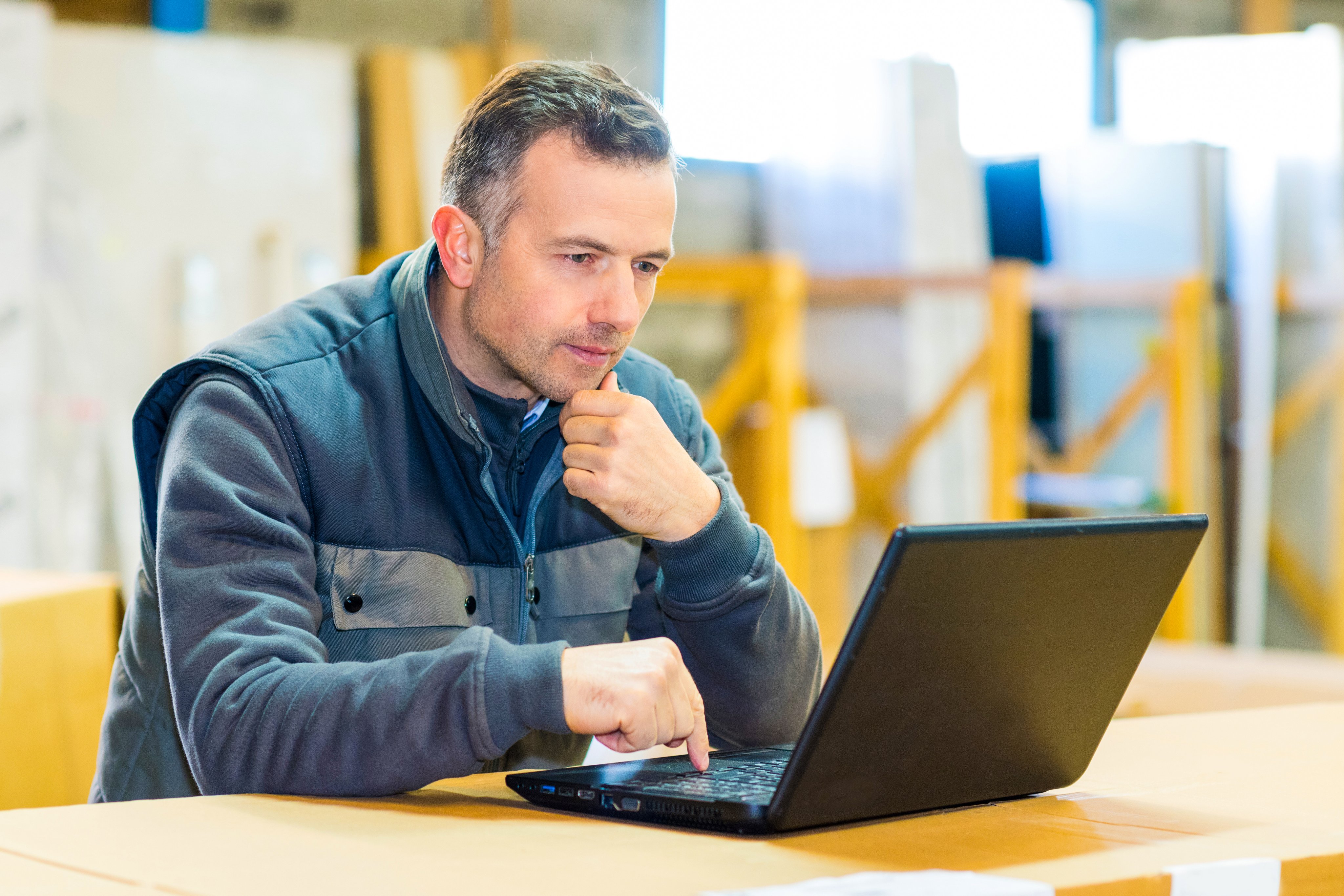 male worker looking at laptop in workshop