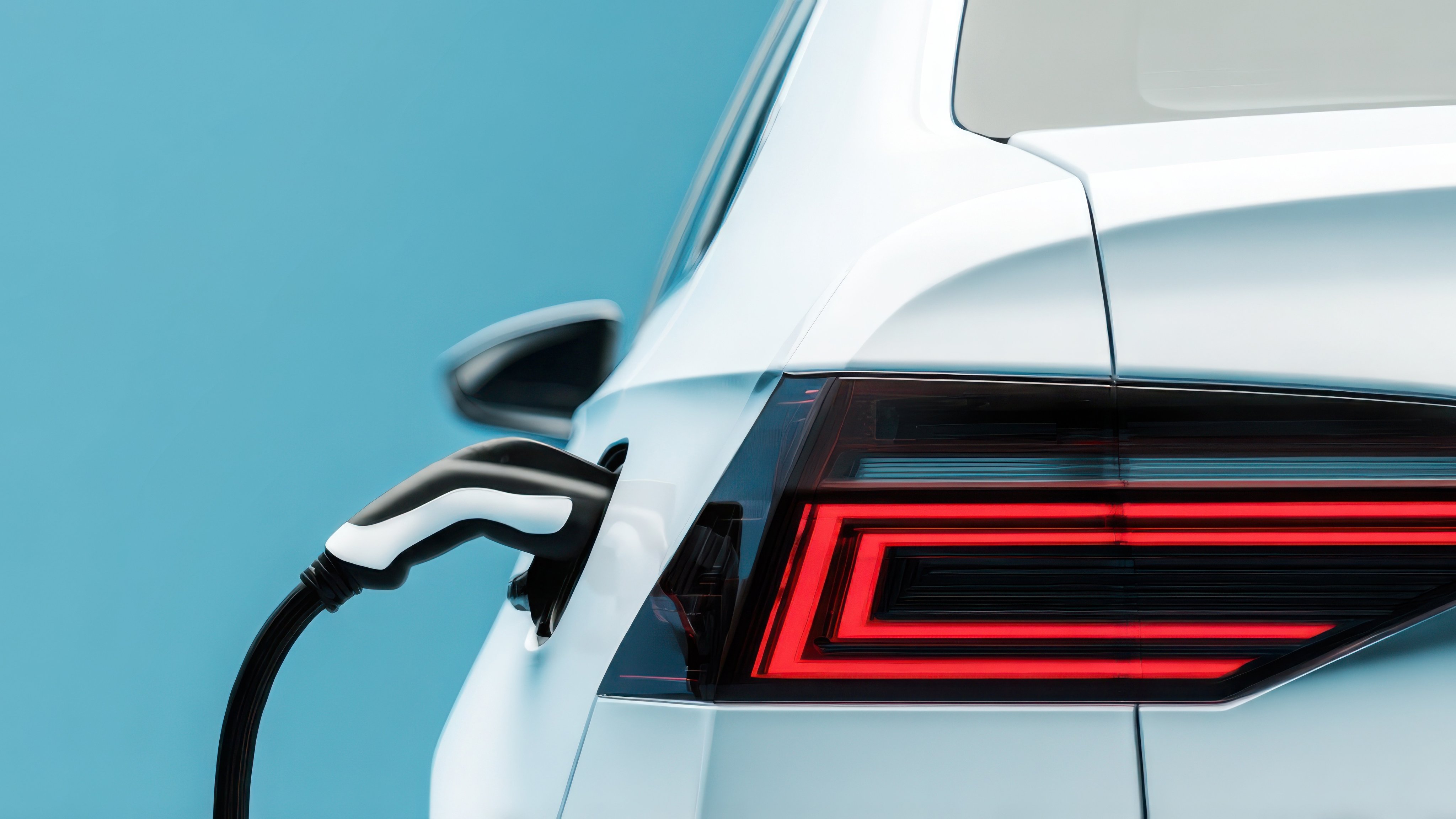 White electric car charging on a background with copy space, a banner design. Close-up of the well-designed tail light of an electric vehicle. The body of a futuristic white and black electronic car. Clean energy concept. Stock photo of the oil and energy industry.