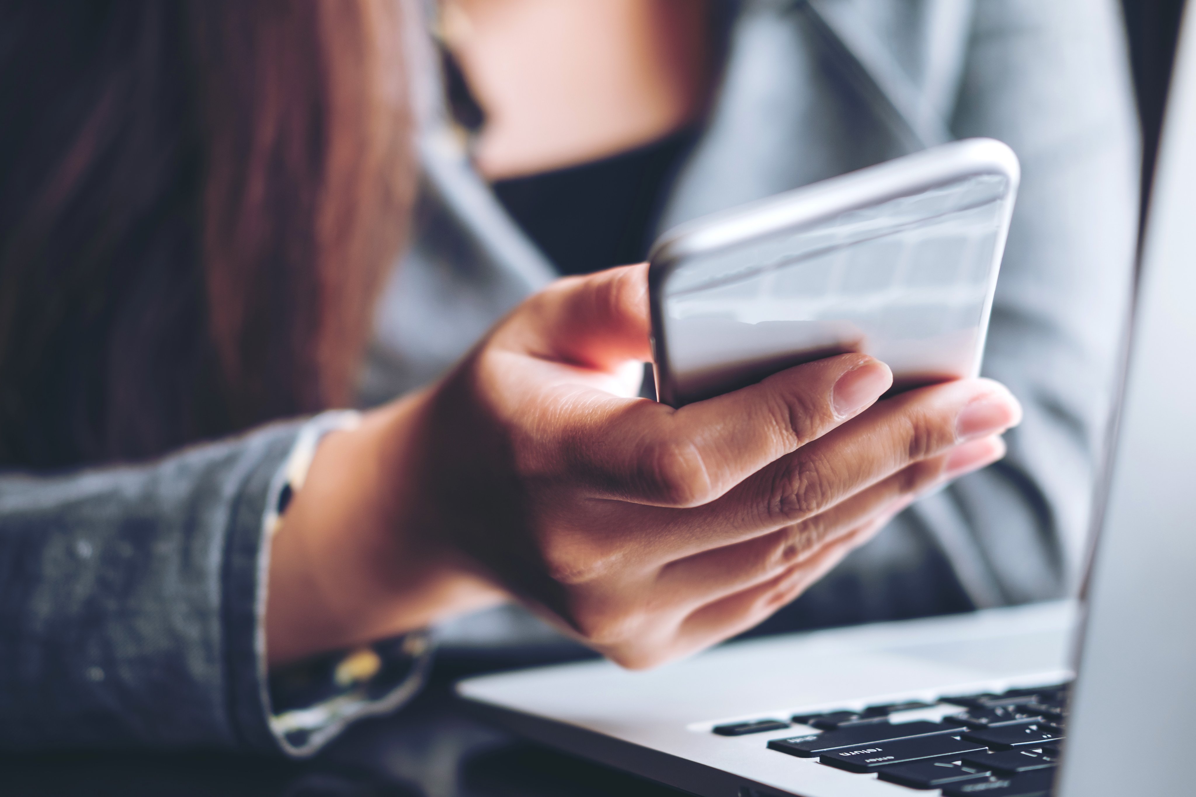 A business woman holding and using smart phone and laptop in office