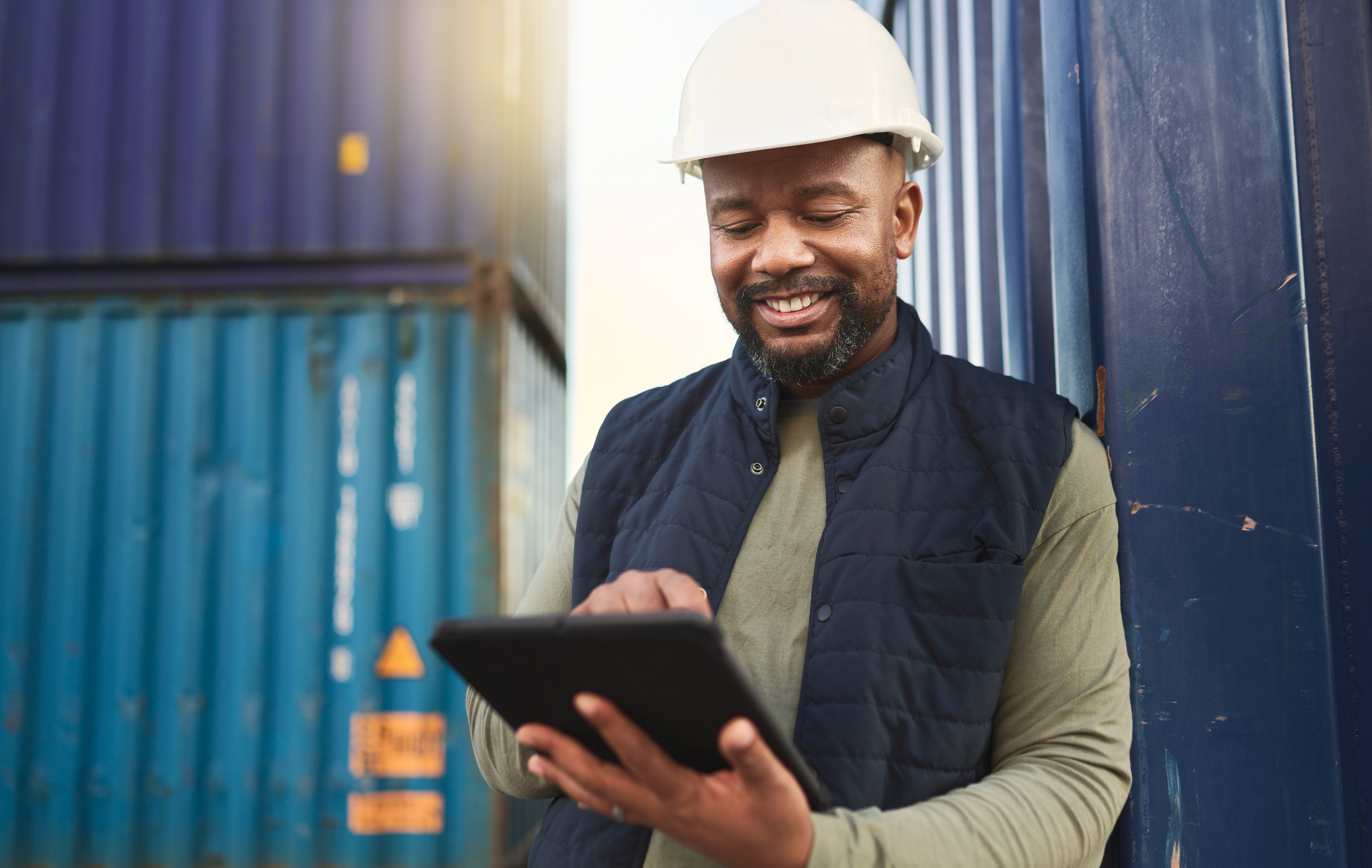 African american shipyard worker, shipping logistics and transportation of international commercial goods. Tablet for inventory management, import and export of cargo in the distribution supply chain.