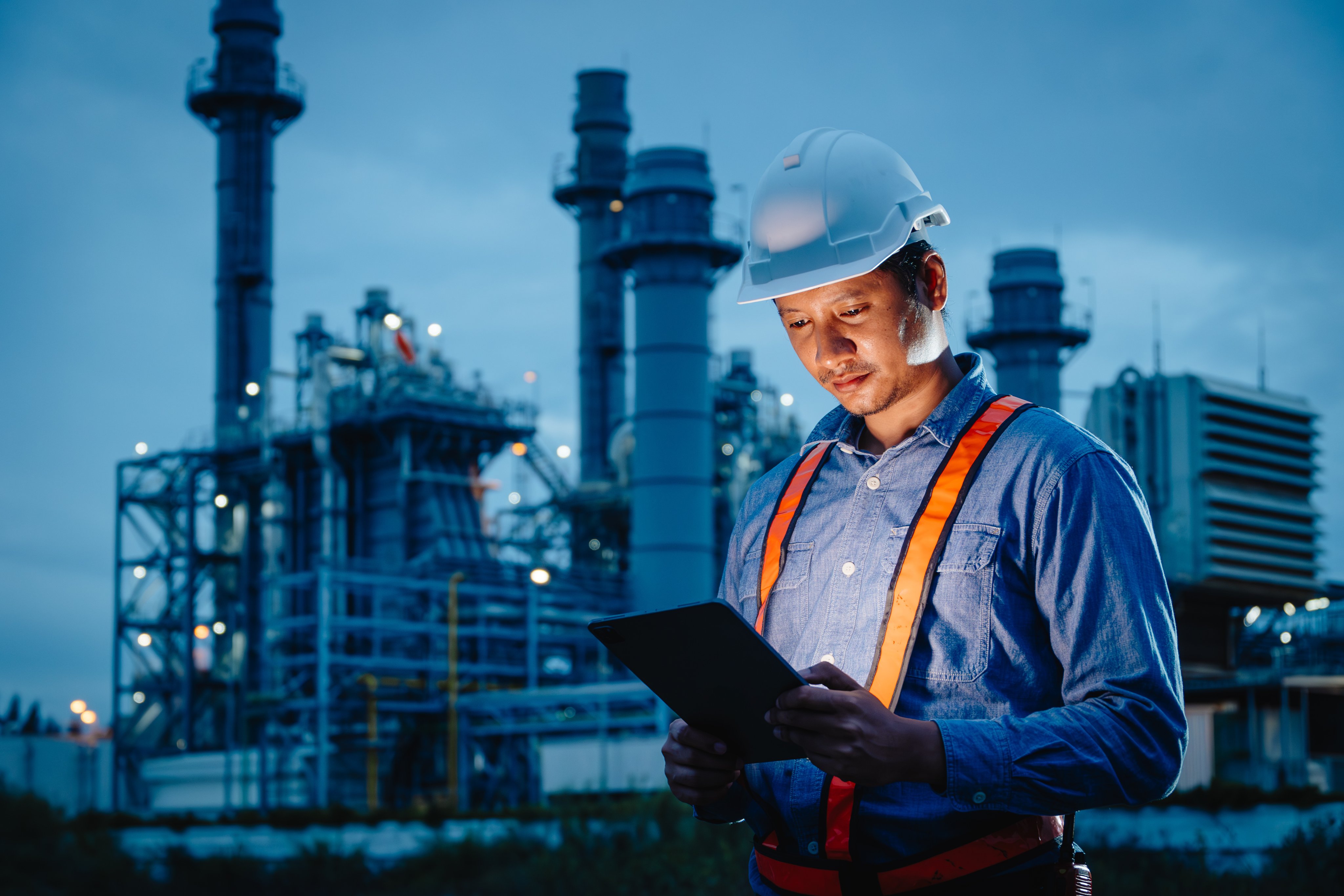 Night shift engineer oil and gas refinery service, male worker hard work in petroleum industry plant dark background.