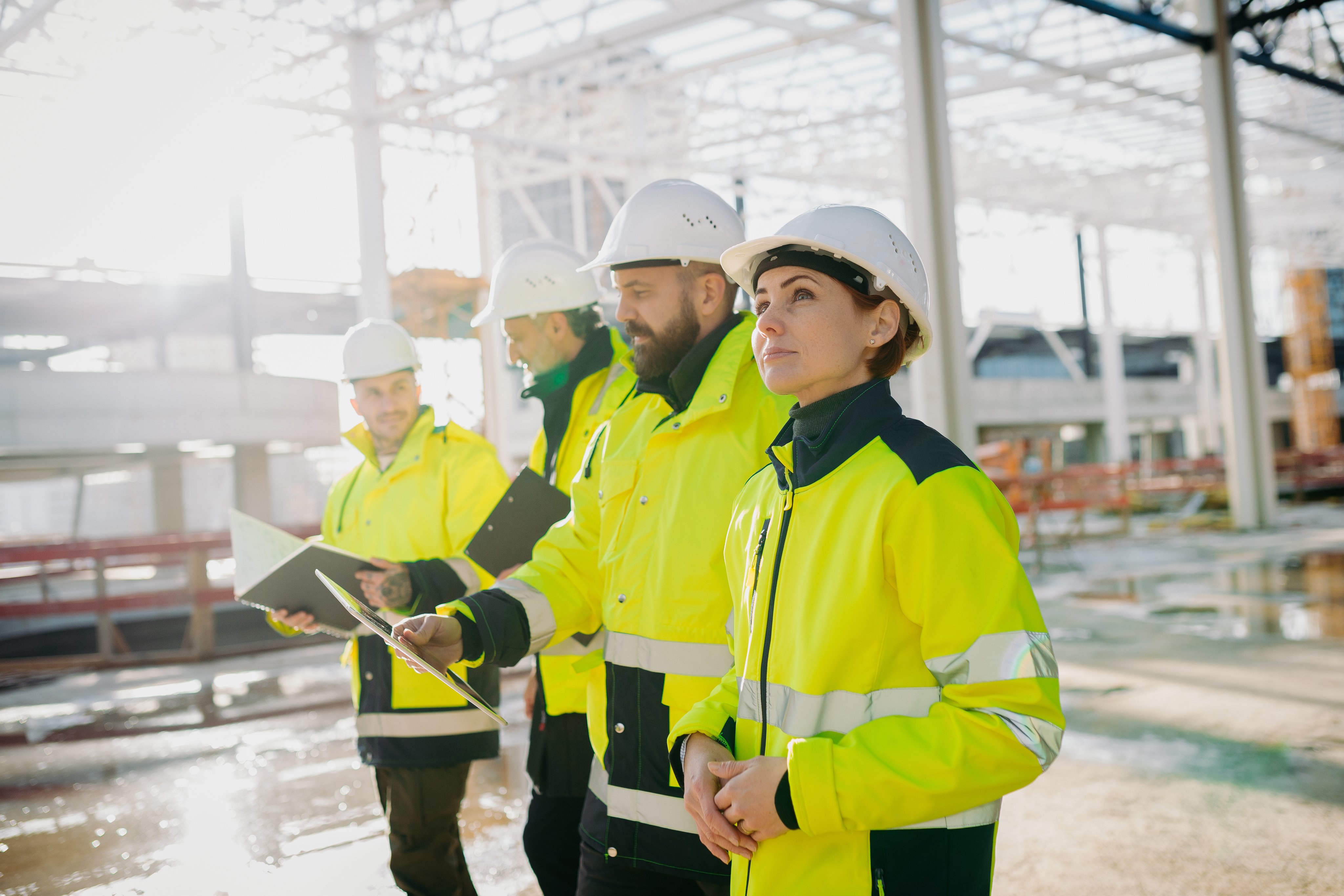 Team of engineers and construction workers inspecting building progress at modern building site.