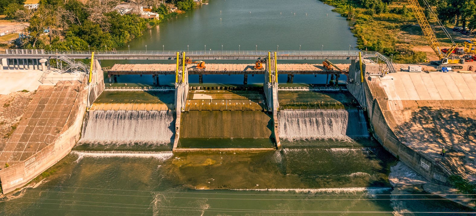 Aerial view of a dam and spillway with construction equipment