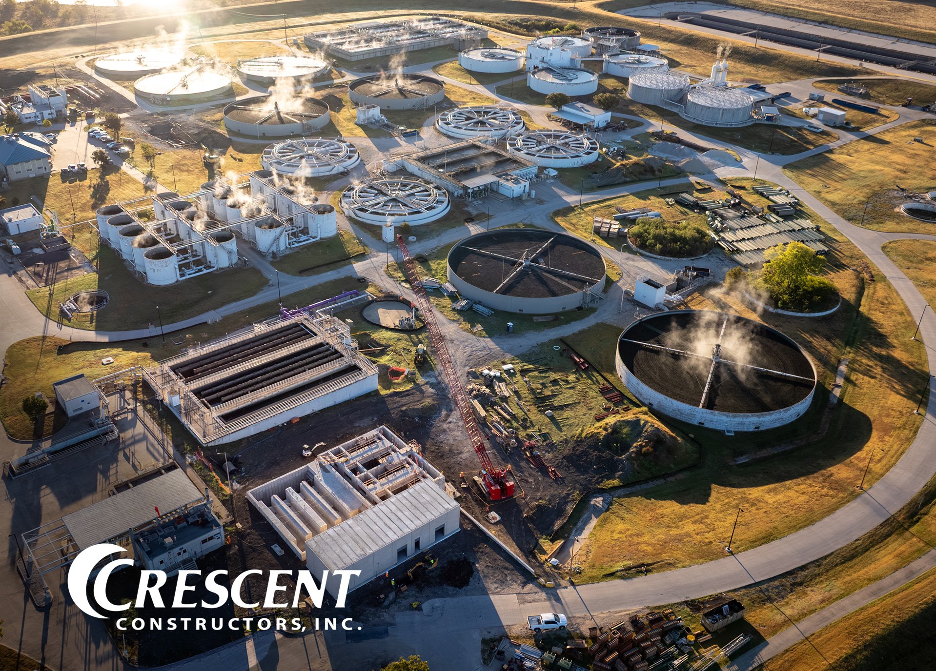 Aerial view of a water and wastewater treatment facility with the Crescent Constructors logo