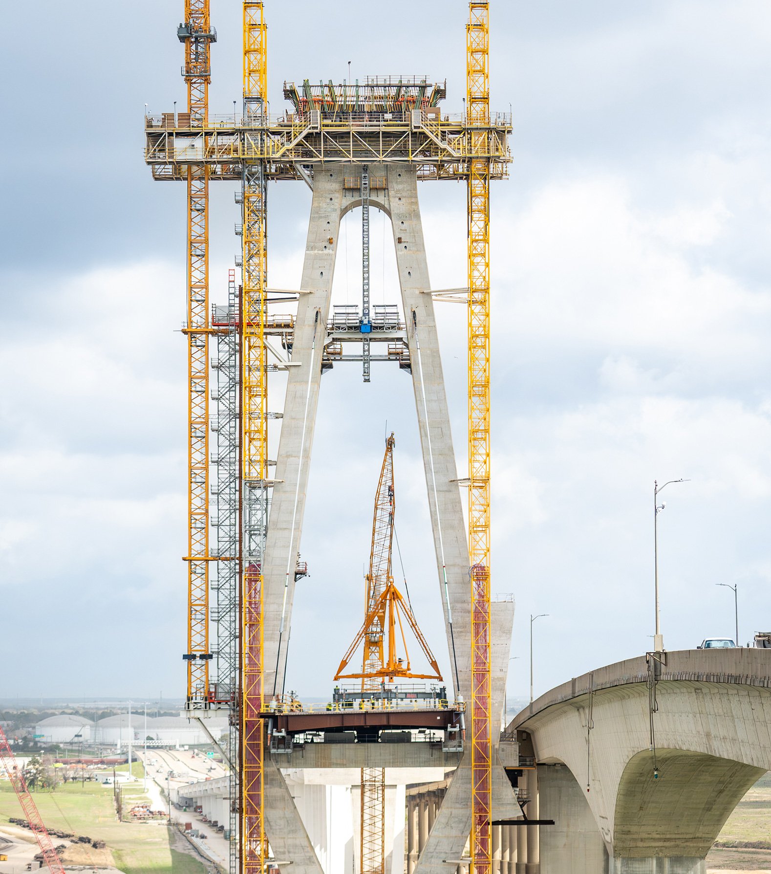 Bridge tower under construction with cranes and elevated roadway structures